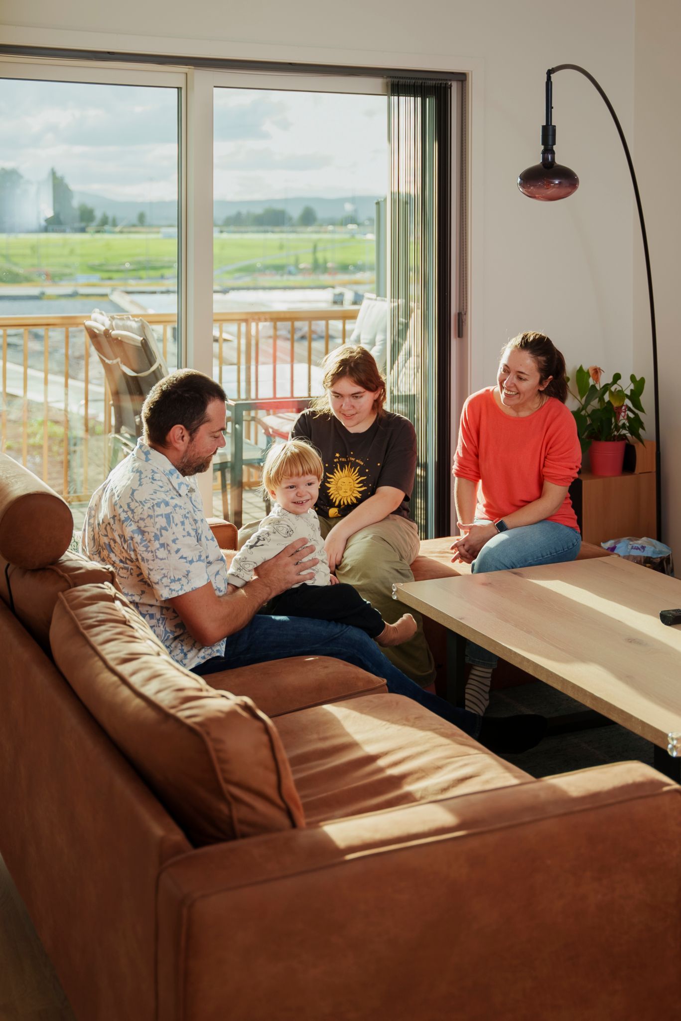 Maja og Nikola med barn sitter i sofaen og ler og koser seg.