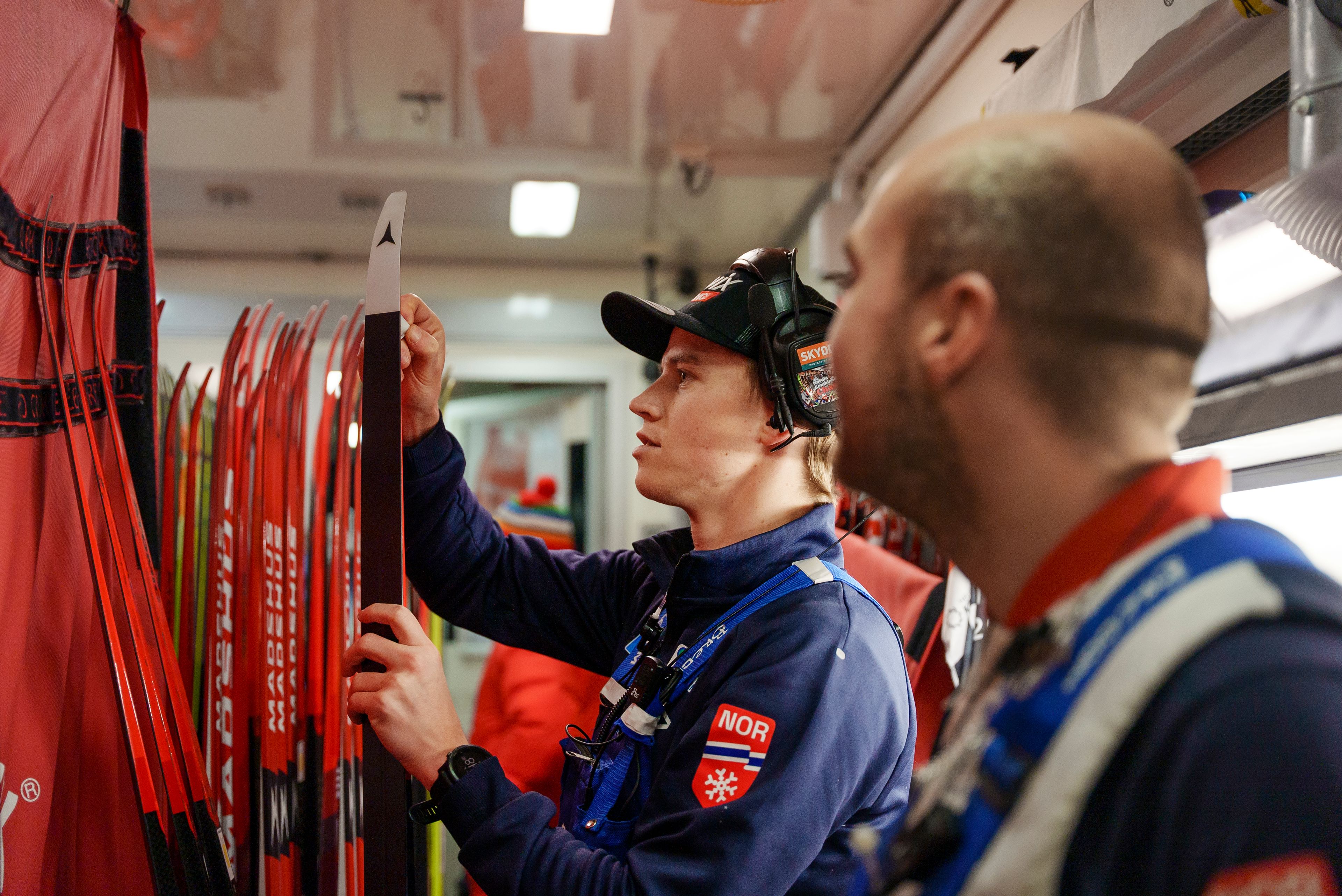 To personer i teamet til Oskar Håland smører ski i smøretraileren.
