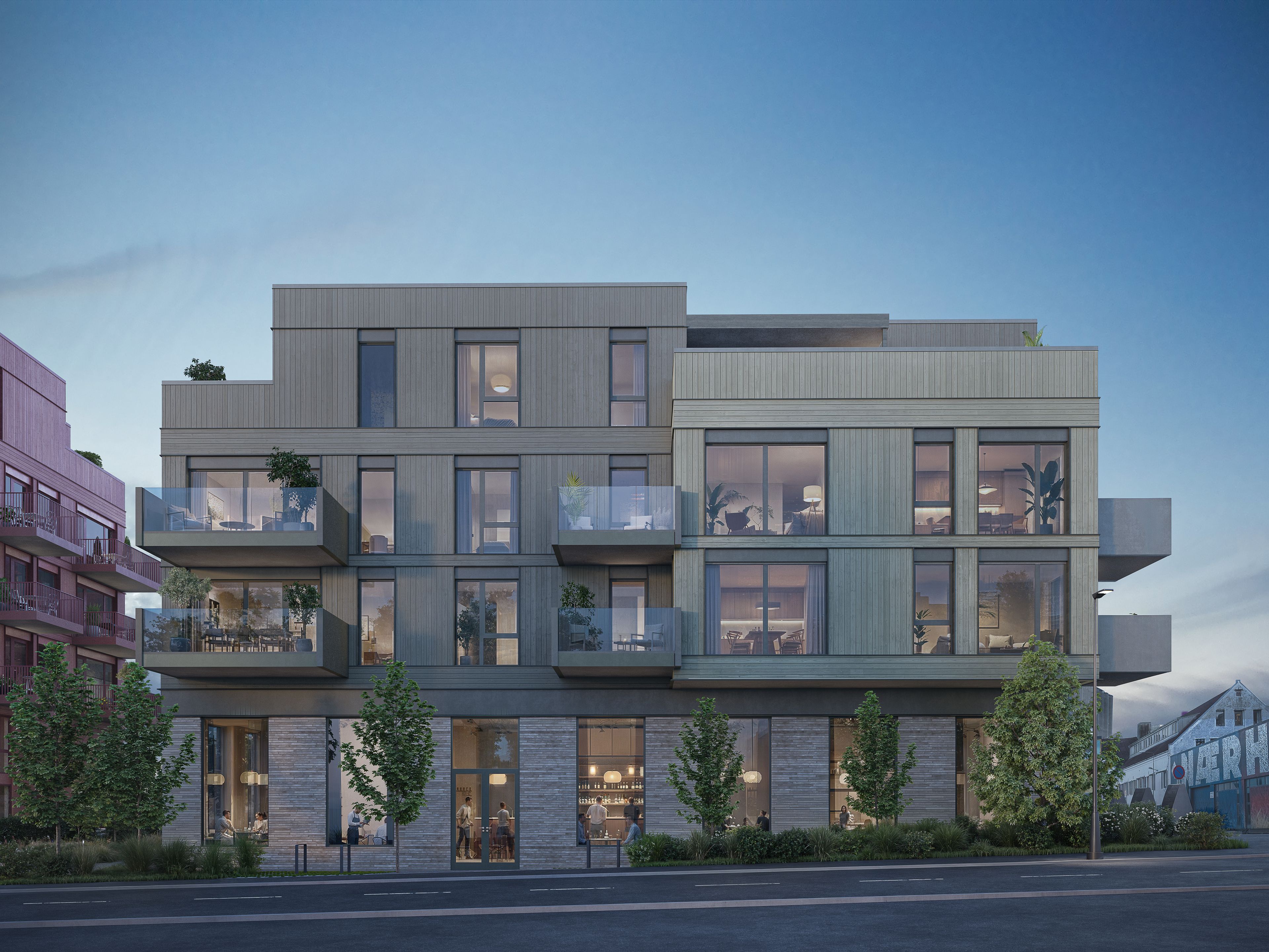 Boligfasader med balkonger og gate med grønn beplantning i forgrunnen.