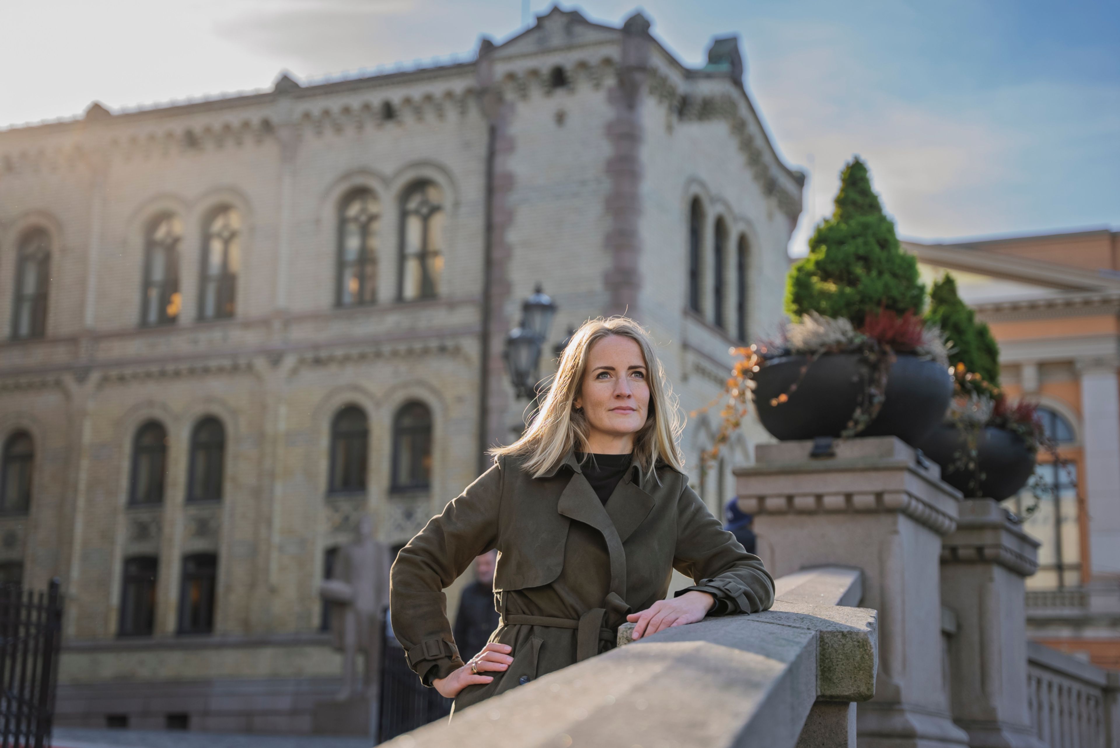 Ingjerd lener seg på det store steingelenderet ved den slake oppoverbakken til Stortingsinngangen.