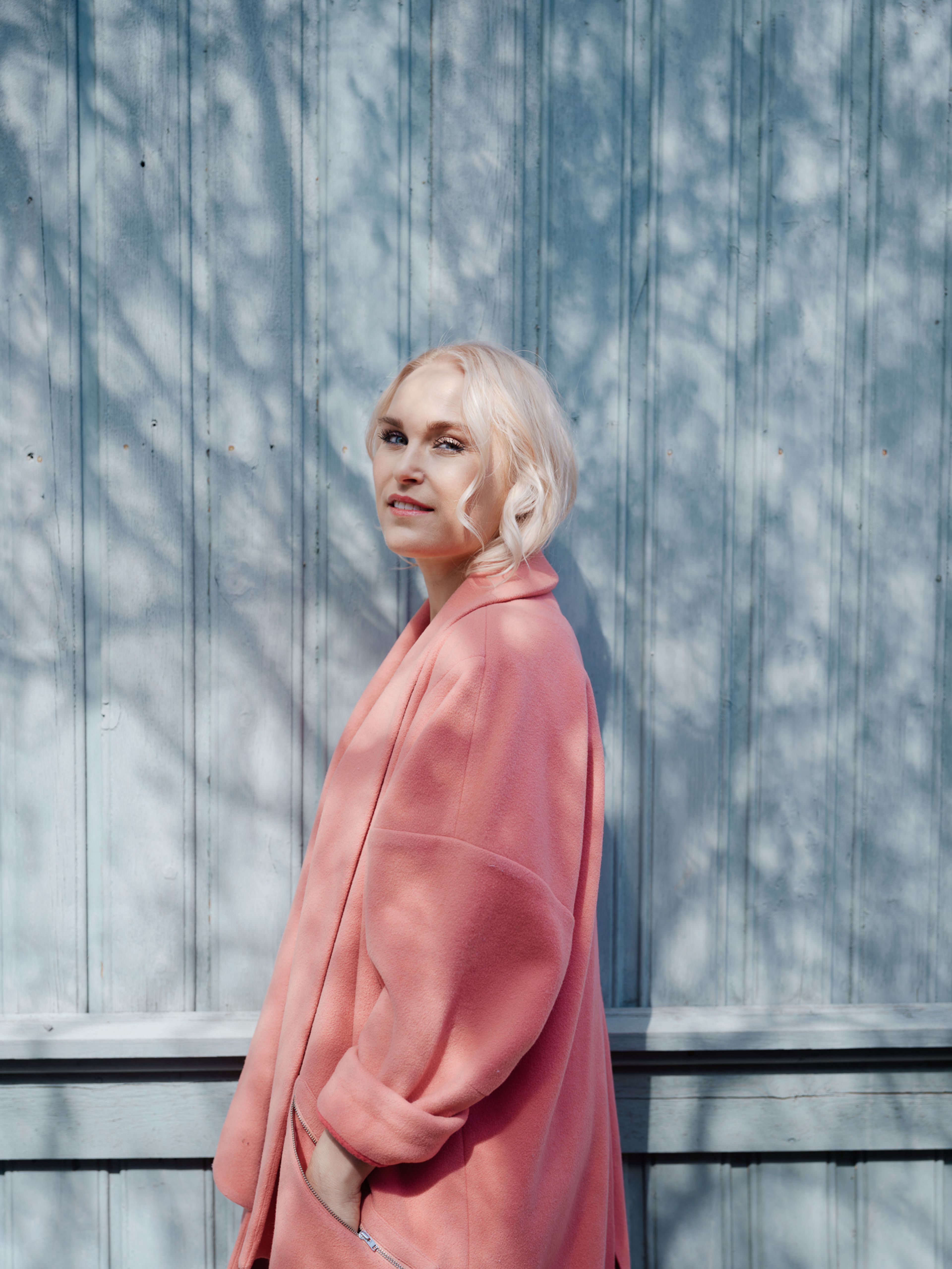 Eva Weel Skram i rosa jakke, foran en blå vegg på Folkemuseet.