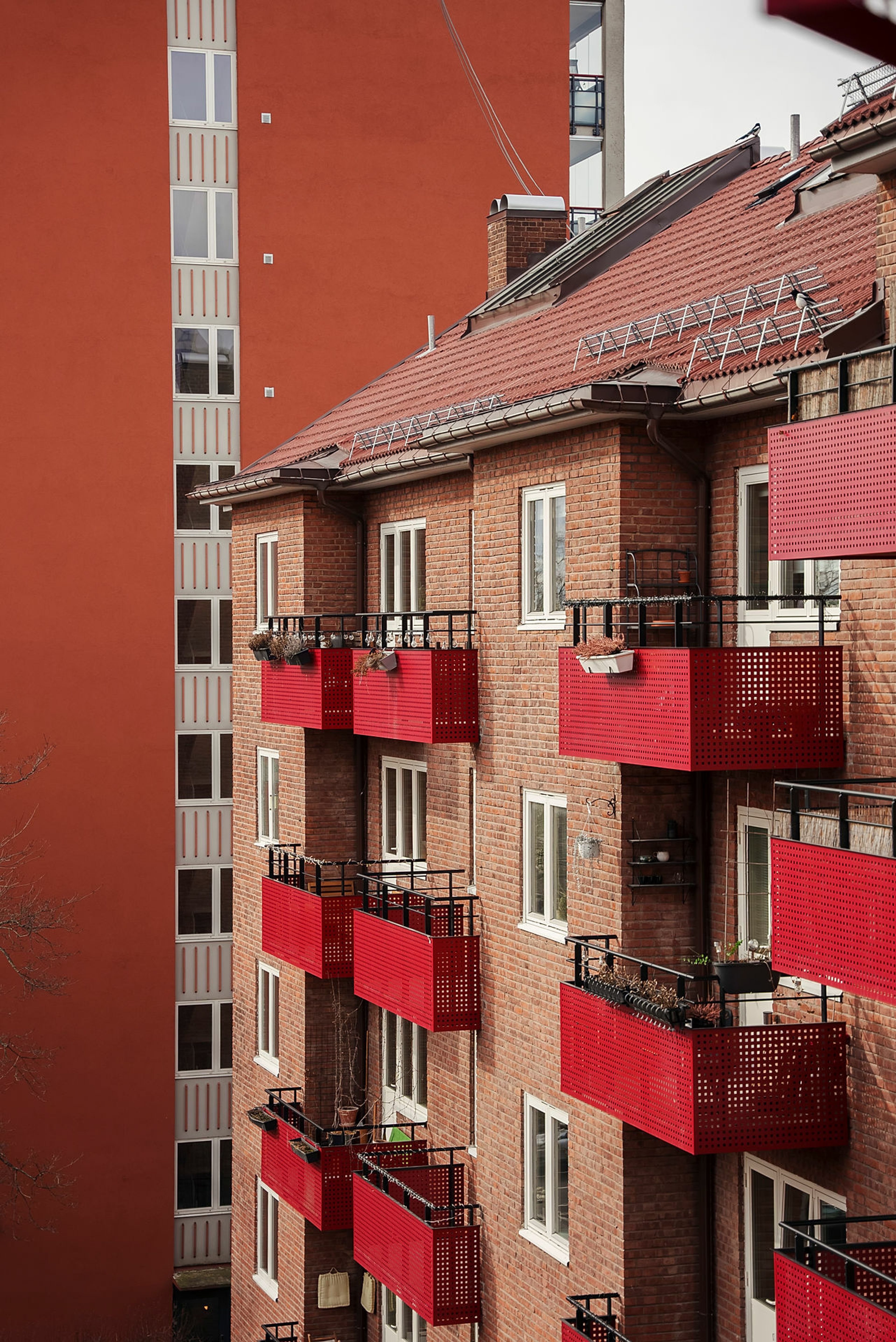 Bakgården til en leilighet, med utsikt over en blokk og en brun mursteinsbygård med røde balkonger.