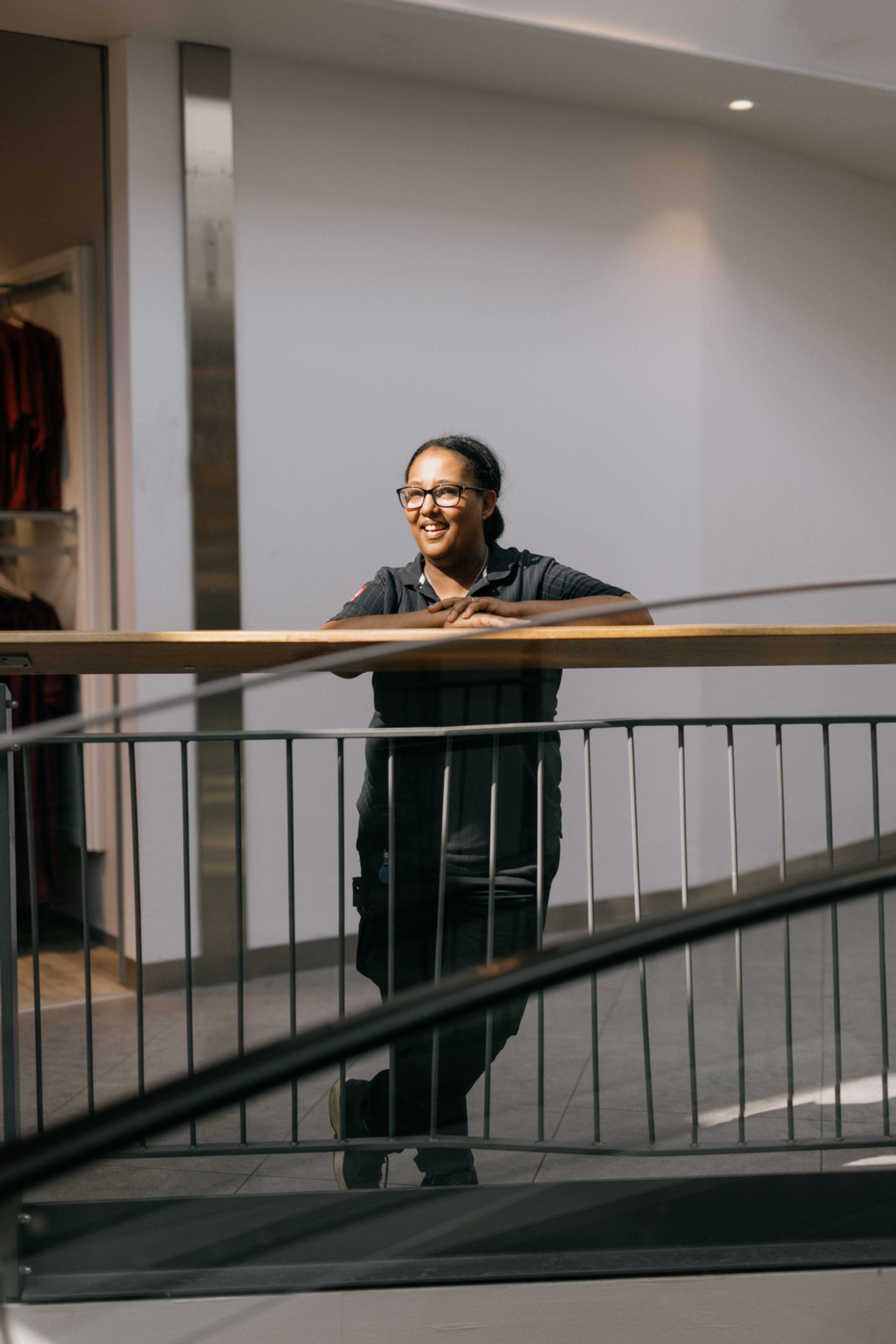 Senait lener seg til et gelender inne på Tveita Senter og smiler.