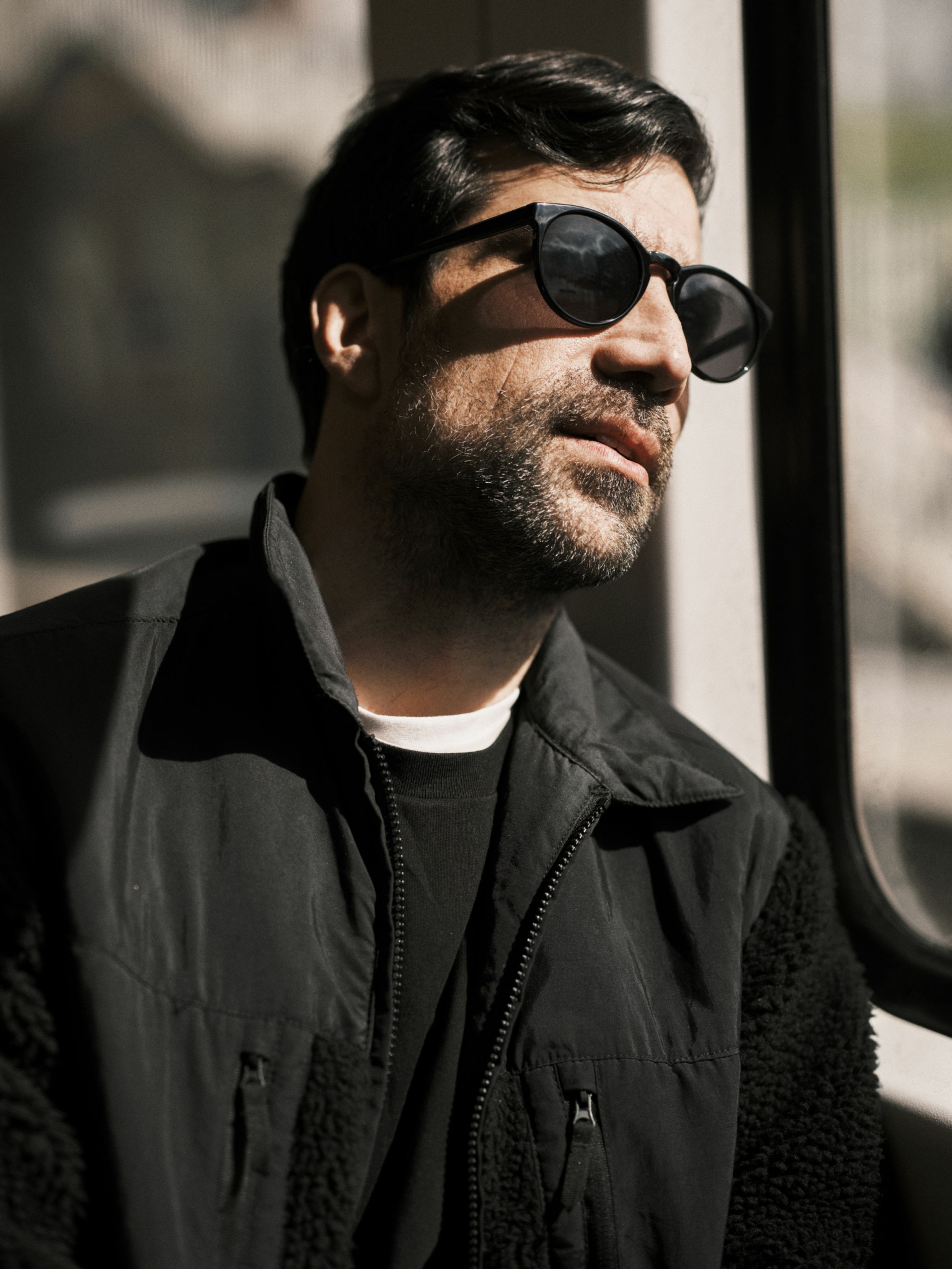 Zeshan Shakar sitter på t-banen med svarte solbriller