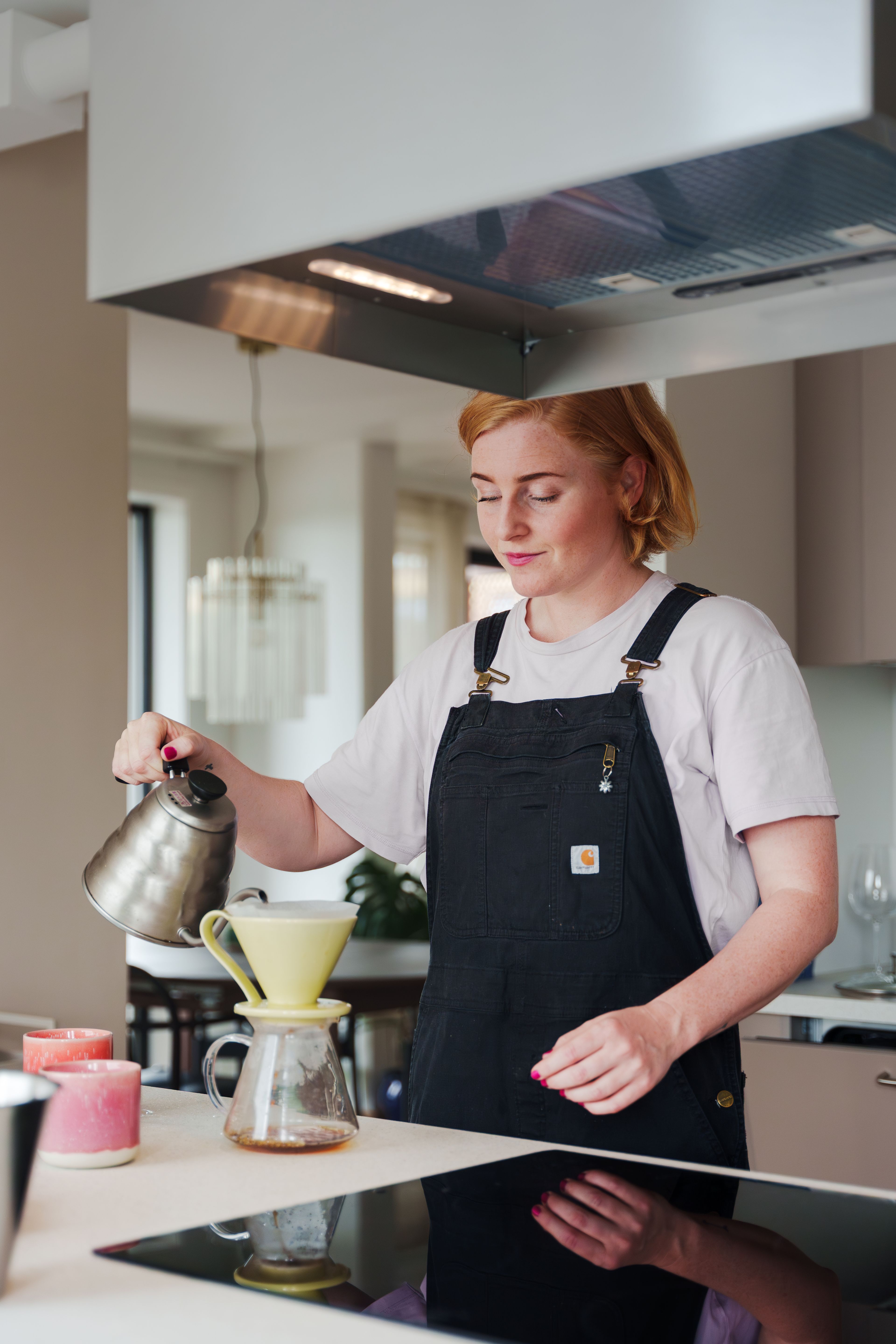 En kvinne står på et kjøkken og trakter kaffe