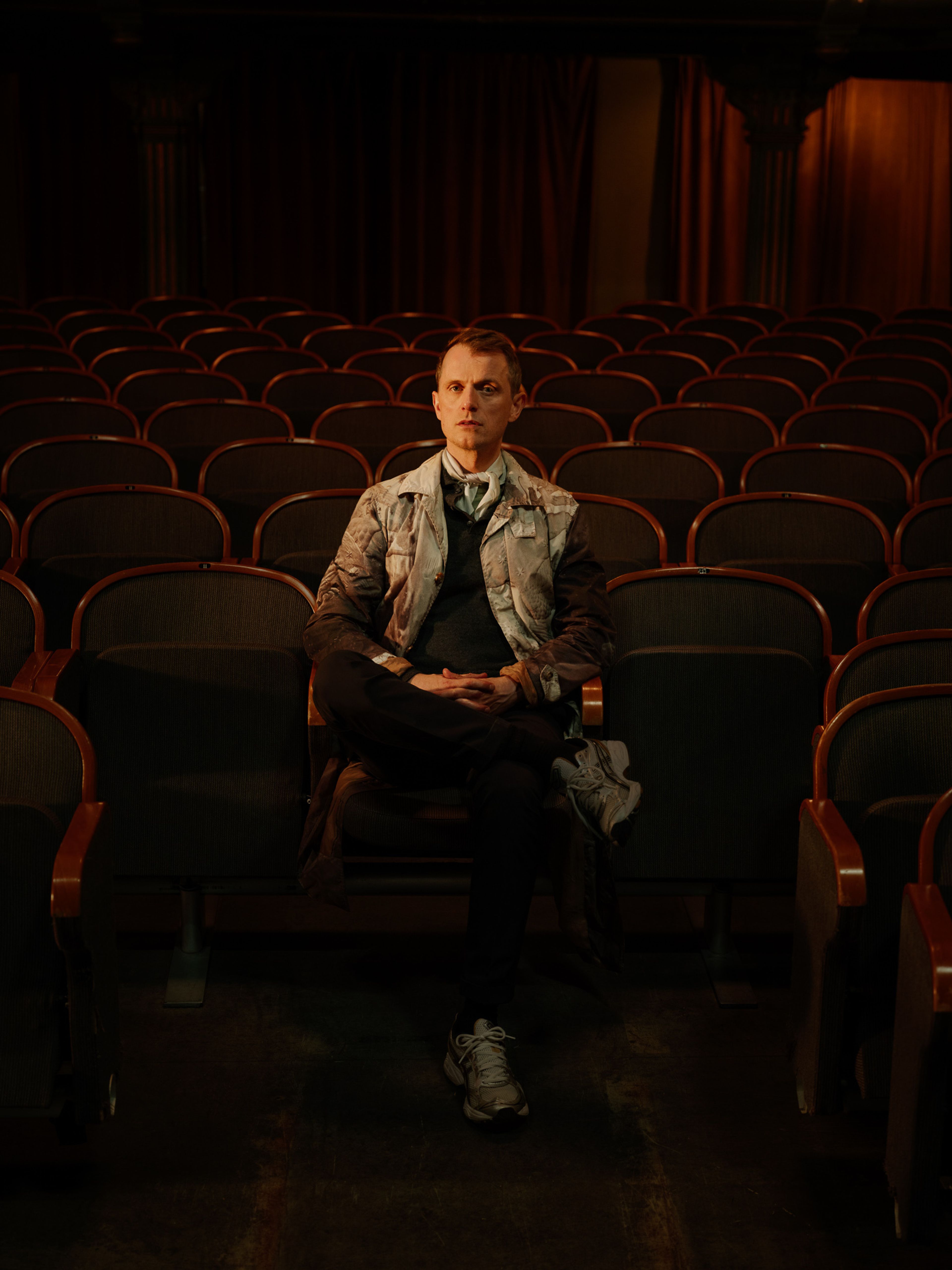Nils Bech ser rett inn i kamera fra sin plass midt i den tomme, mørke salen på Centralteatret