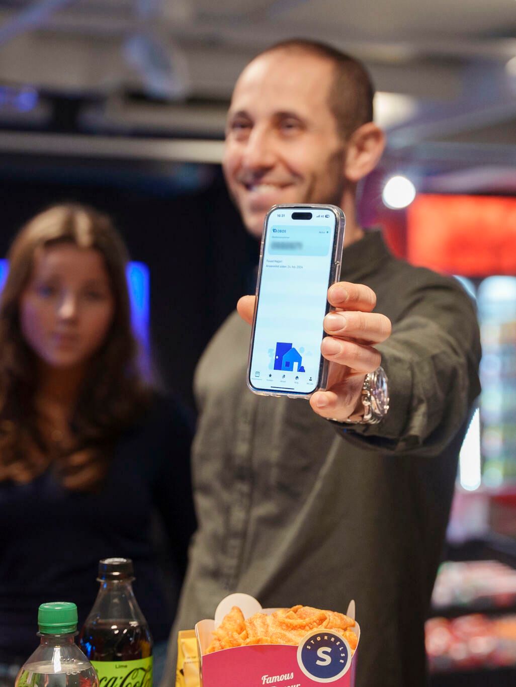 En mann og to barn står på ODEON Kino. Han viser fram OBOS-appen.