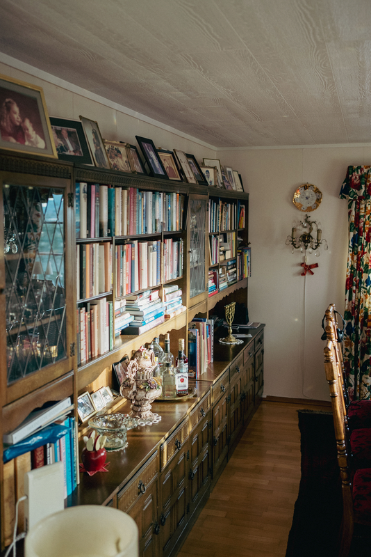 Bilde av noen av Svein og Unni sine mørke bokhyller, med skuffer under dem