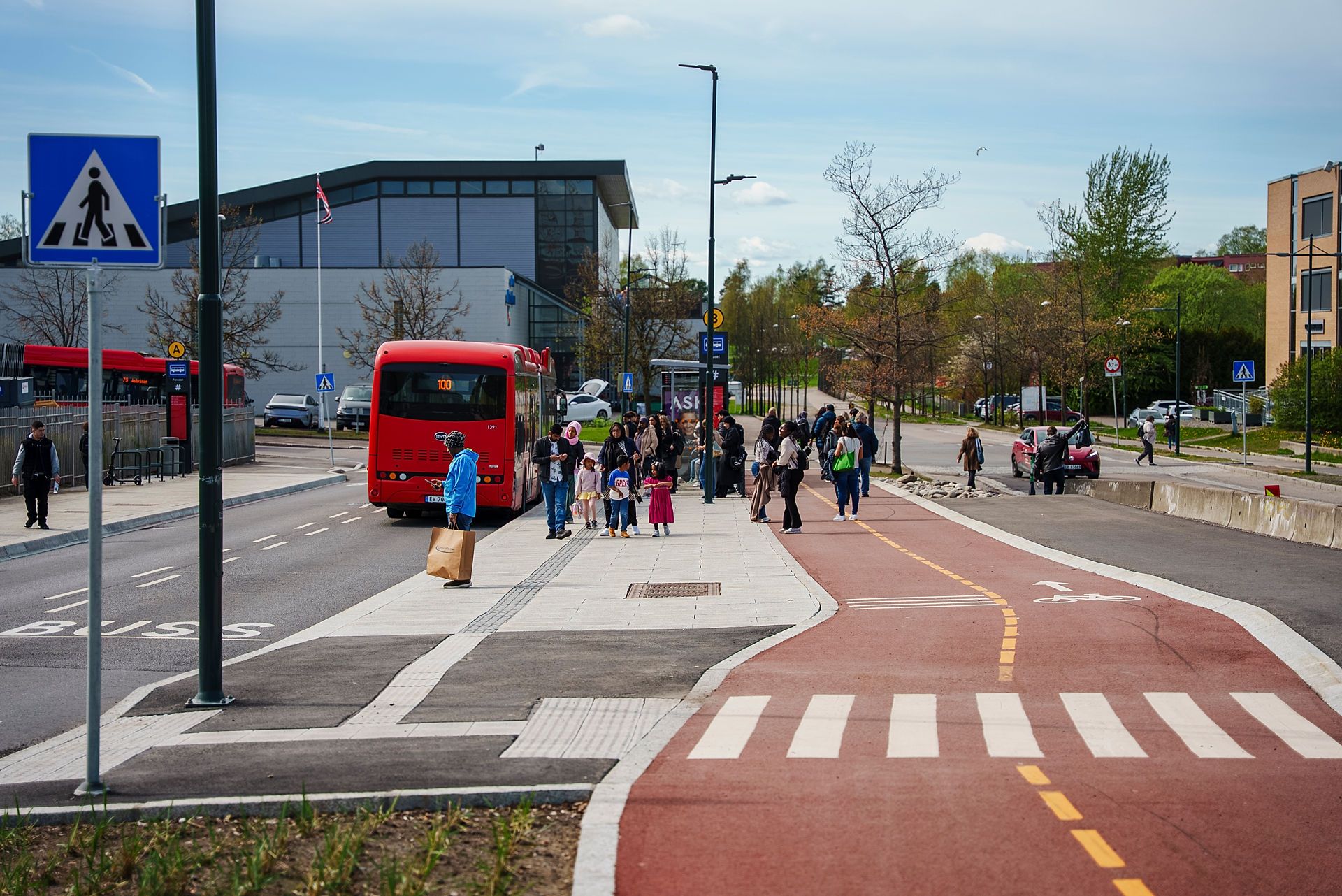 Bilde av en nylagt sykkelvei på Furuset. Ved siden av ser vi at bussen stopper på en ny bussholdeplass, hvor mange folk venter på bussen.