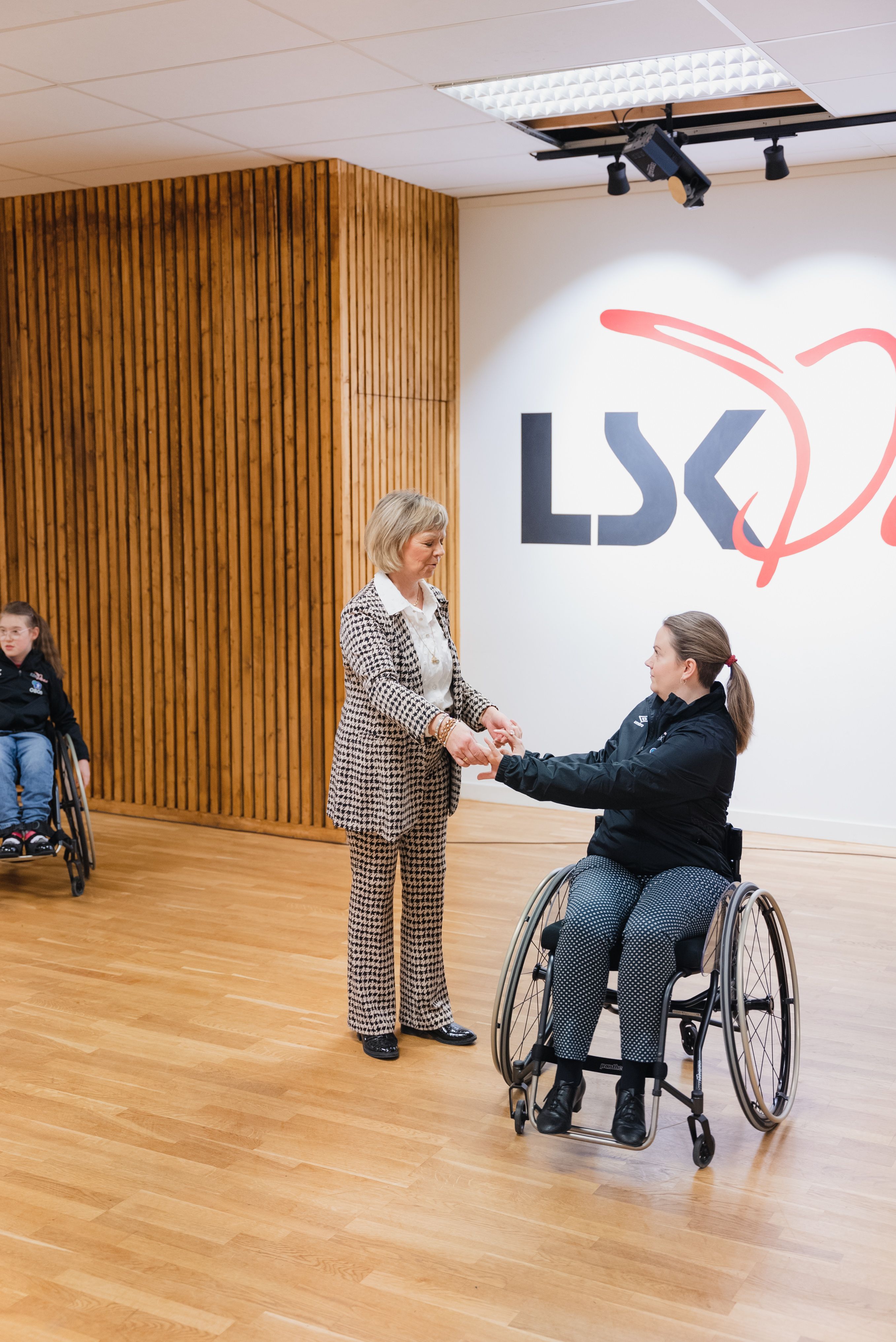 Trine Dehli Cleve danser sammen med en av instruktørene i rullestol.