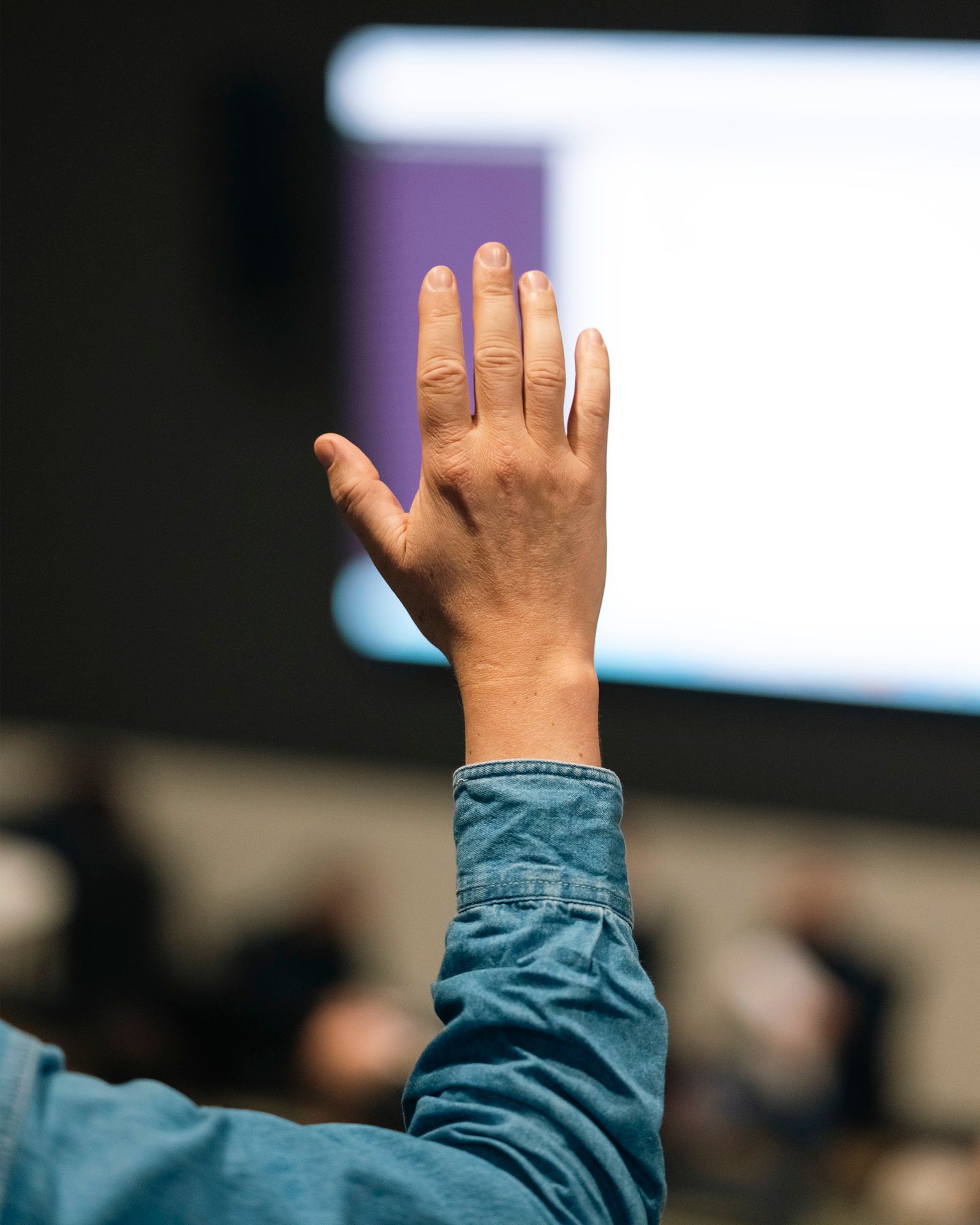 En hånd holdes oppe for å avgi stemme på en generalforsamling.