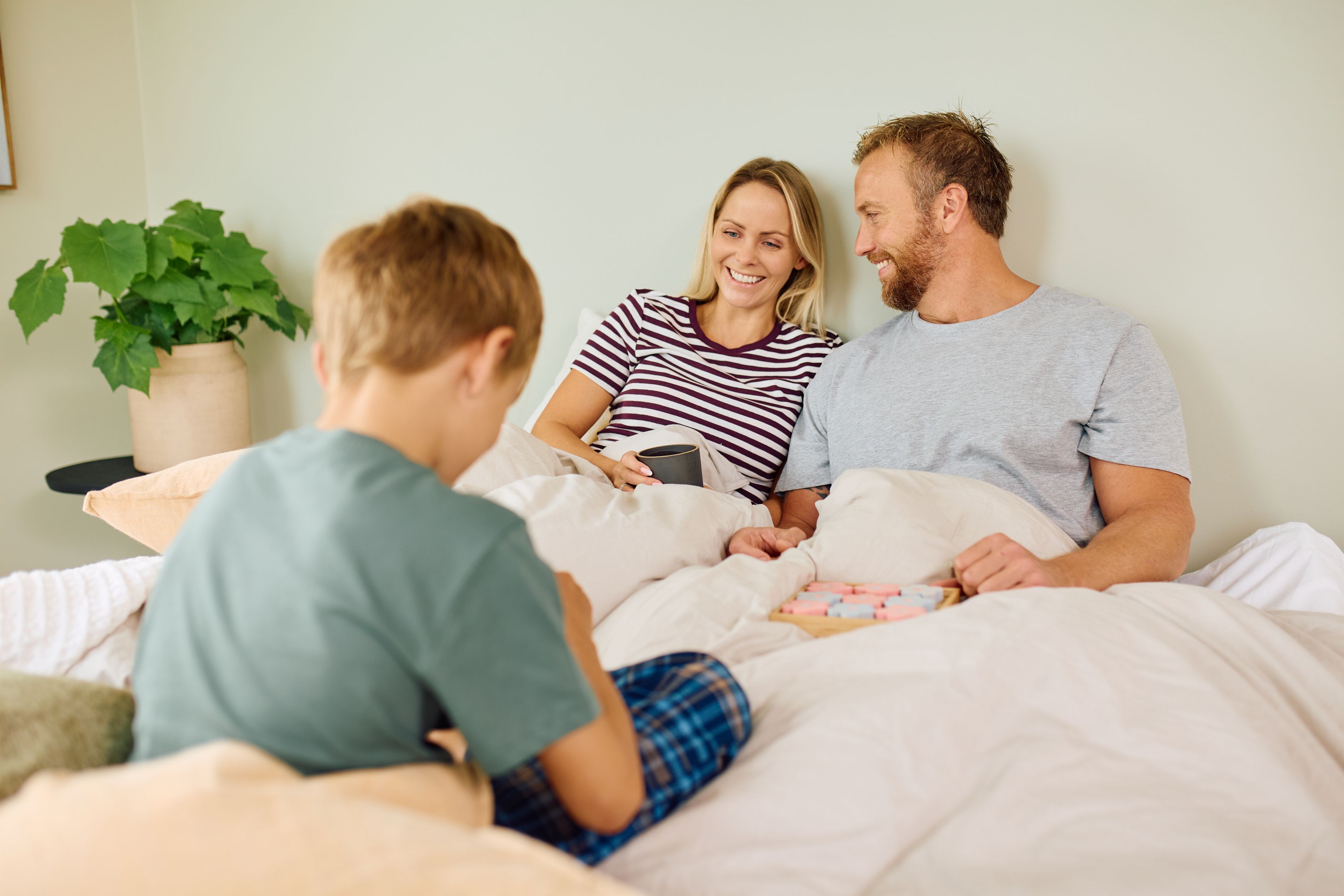 En mann og en dame er i lag med tre barn. De leker og mannen smiler bredt.