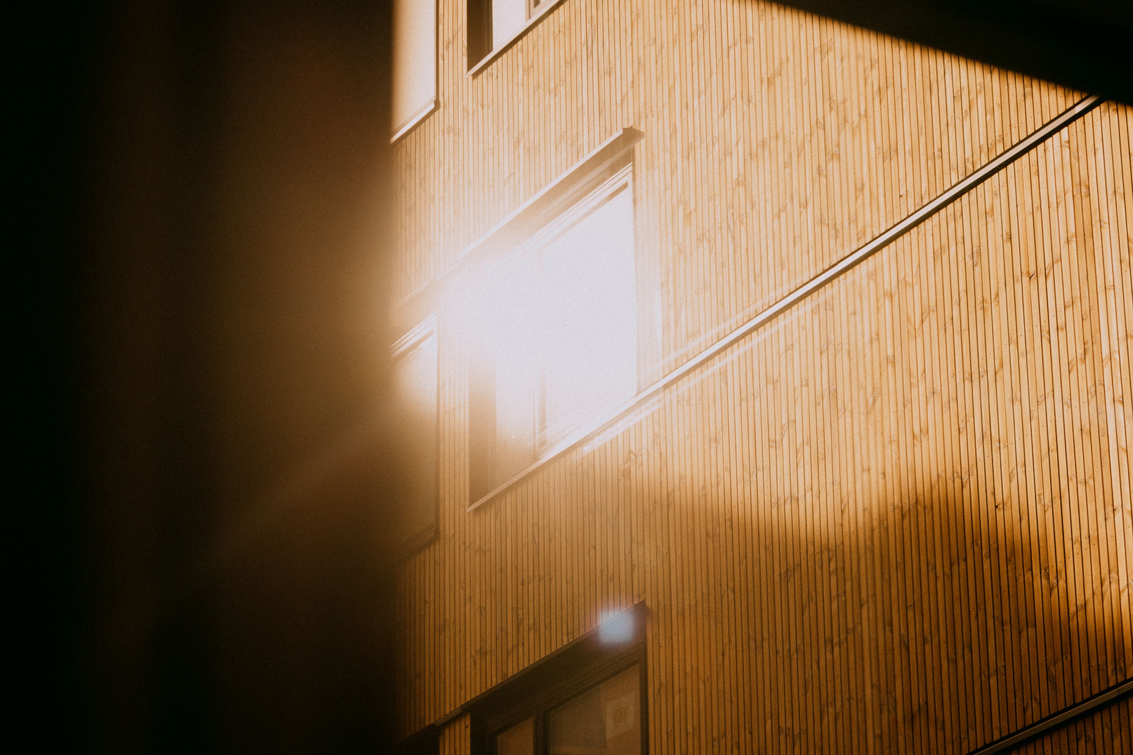 Bilde av fasade, hvor solen speiler seg i et vindu i Løren botaniske.