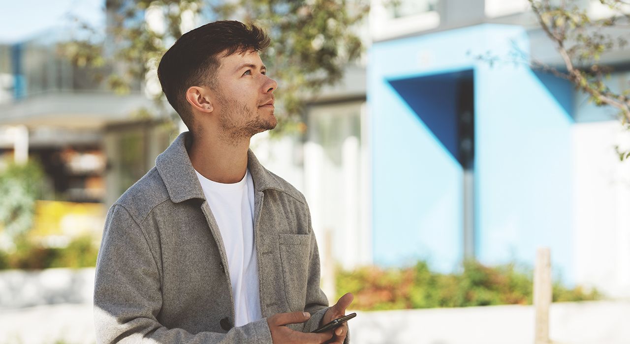 En ung mann ser mot boligblokken sin.