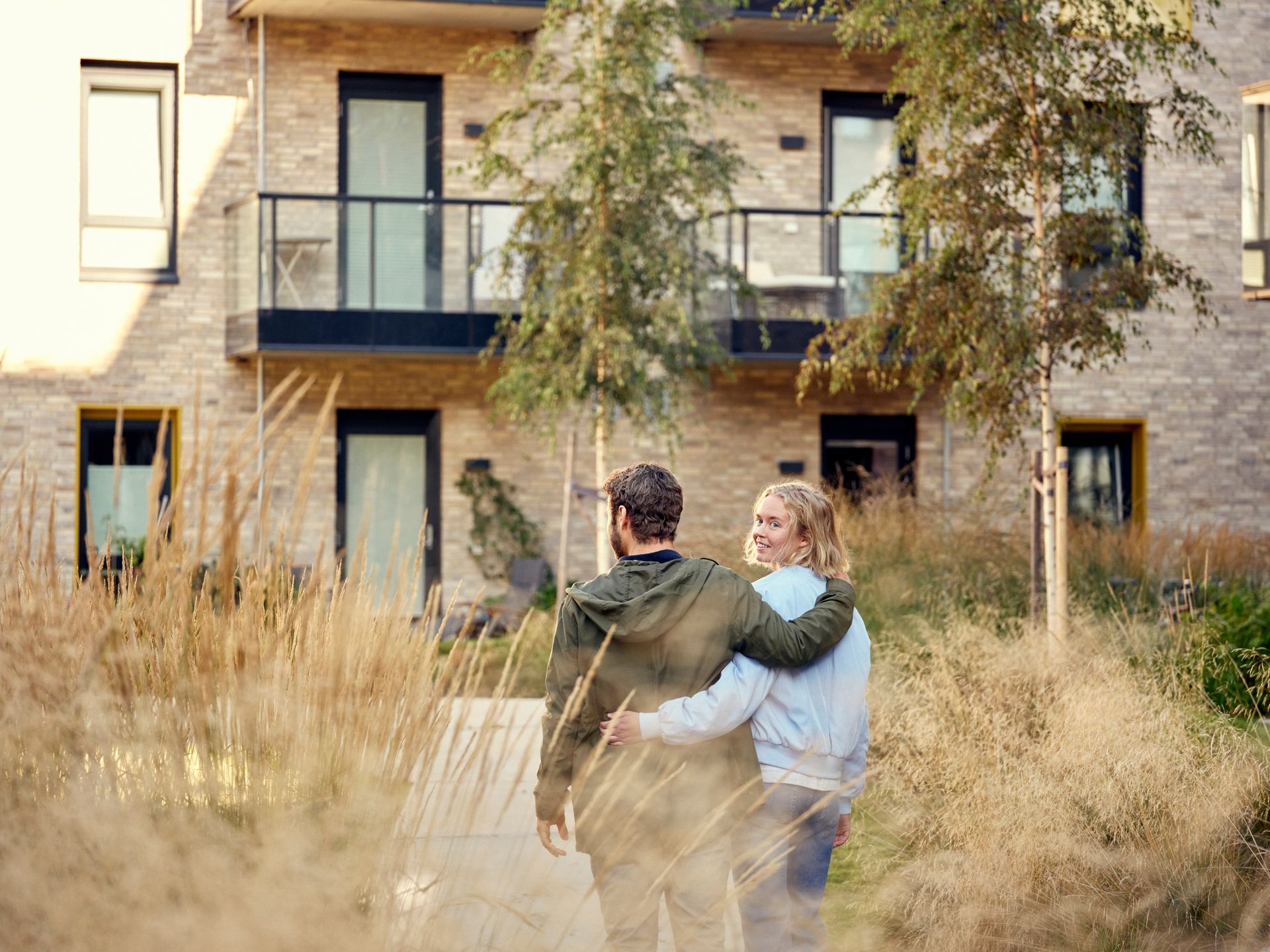 Et ungt par går foran en boligblokk.