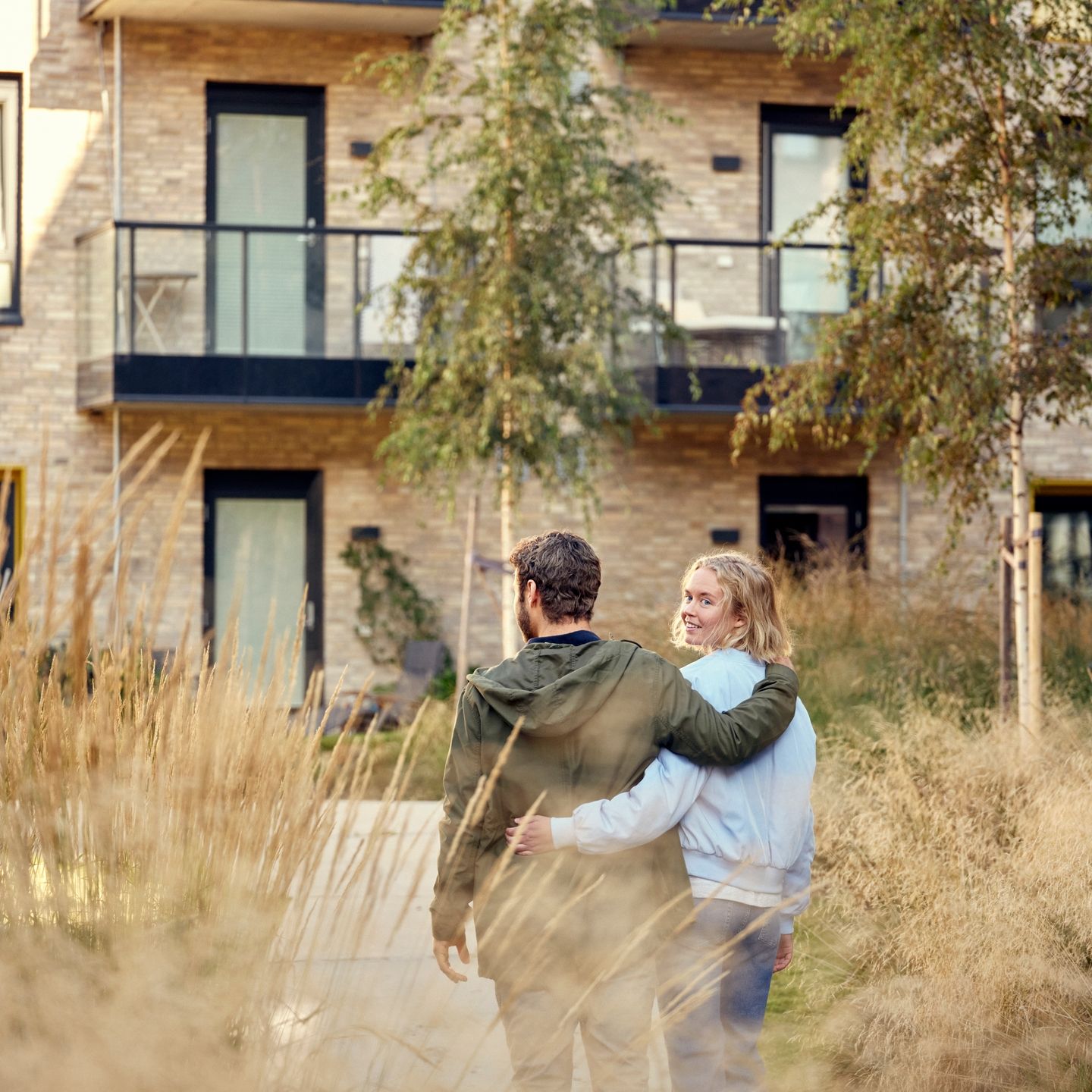 Et ungt par går foran en boligblokk.