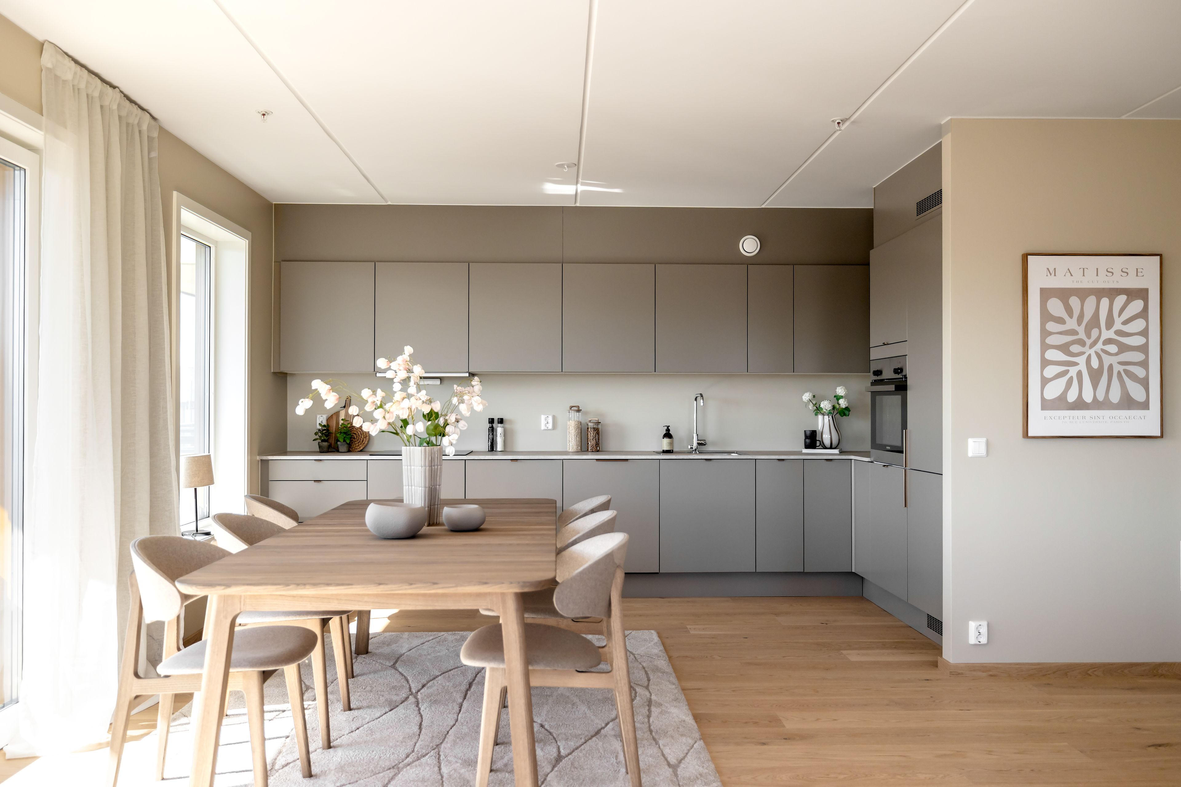 foto av spisestue med seks stoler foran kjøkken med beige fronter