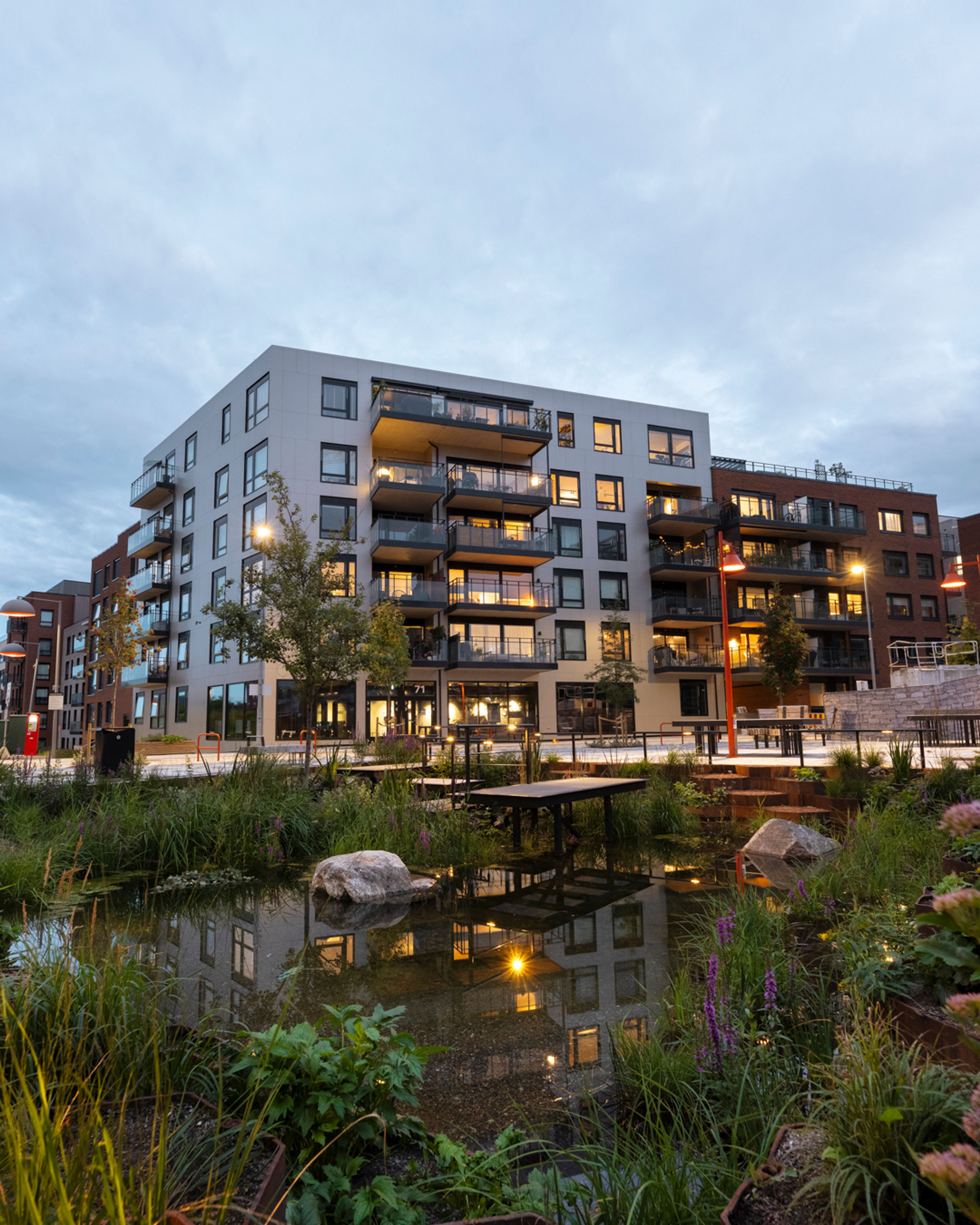 Foto av fasadene til boligprosjektene på Vollebekk med en dam.
