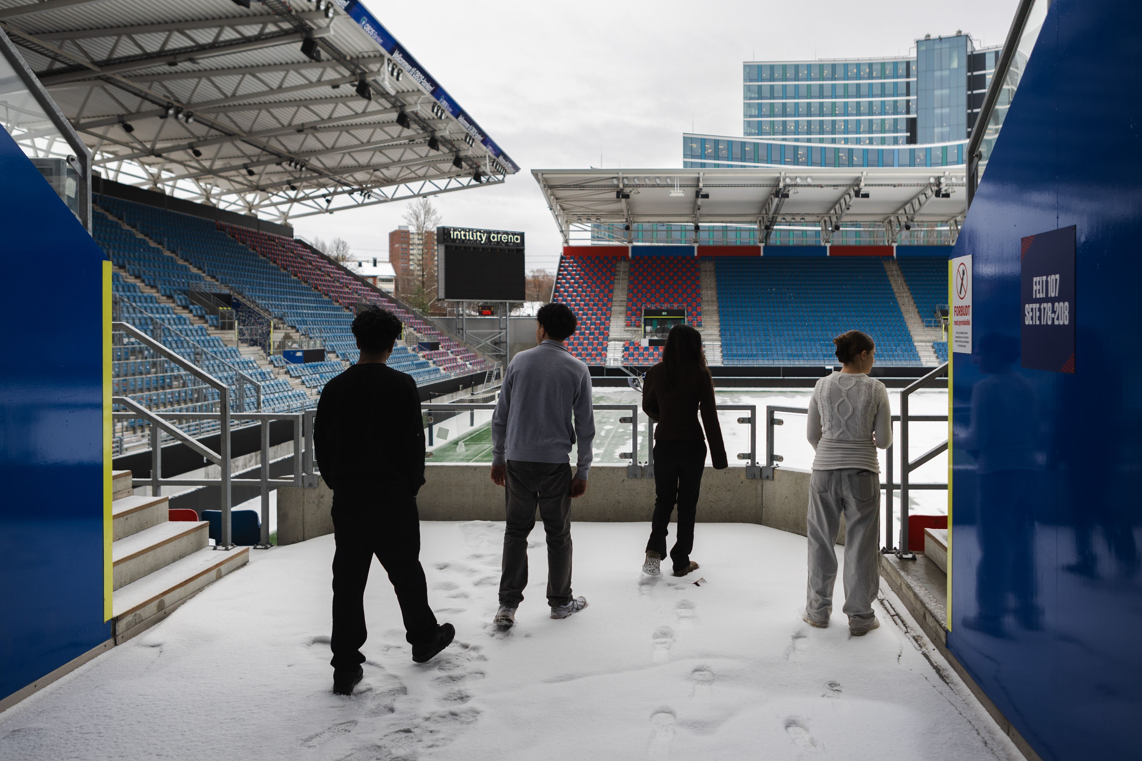 Fire ungdommer går inn på en fotballstadion.