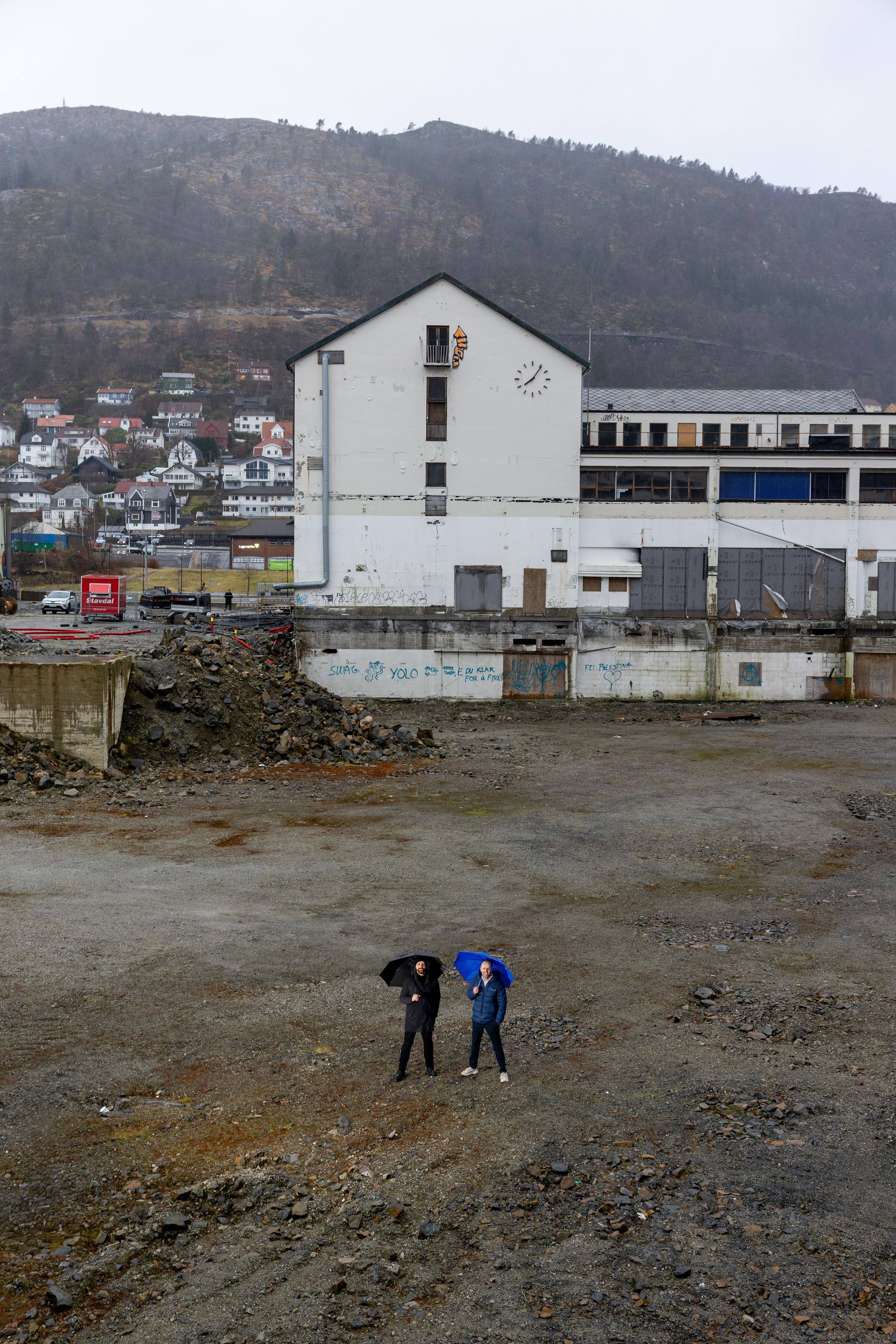 Arkitekt Fredrik Barth og prosjektleder Frode Rønhovde står midt på en grusplass og titter opp mot kamera.