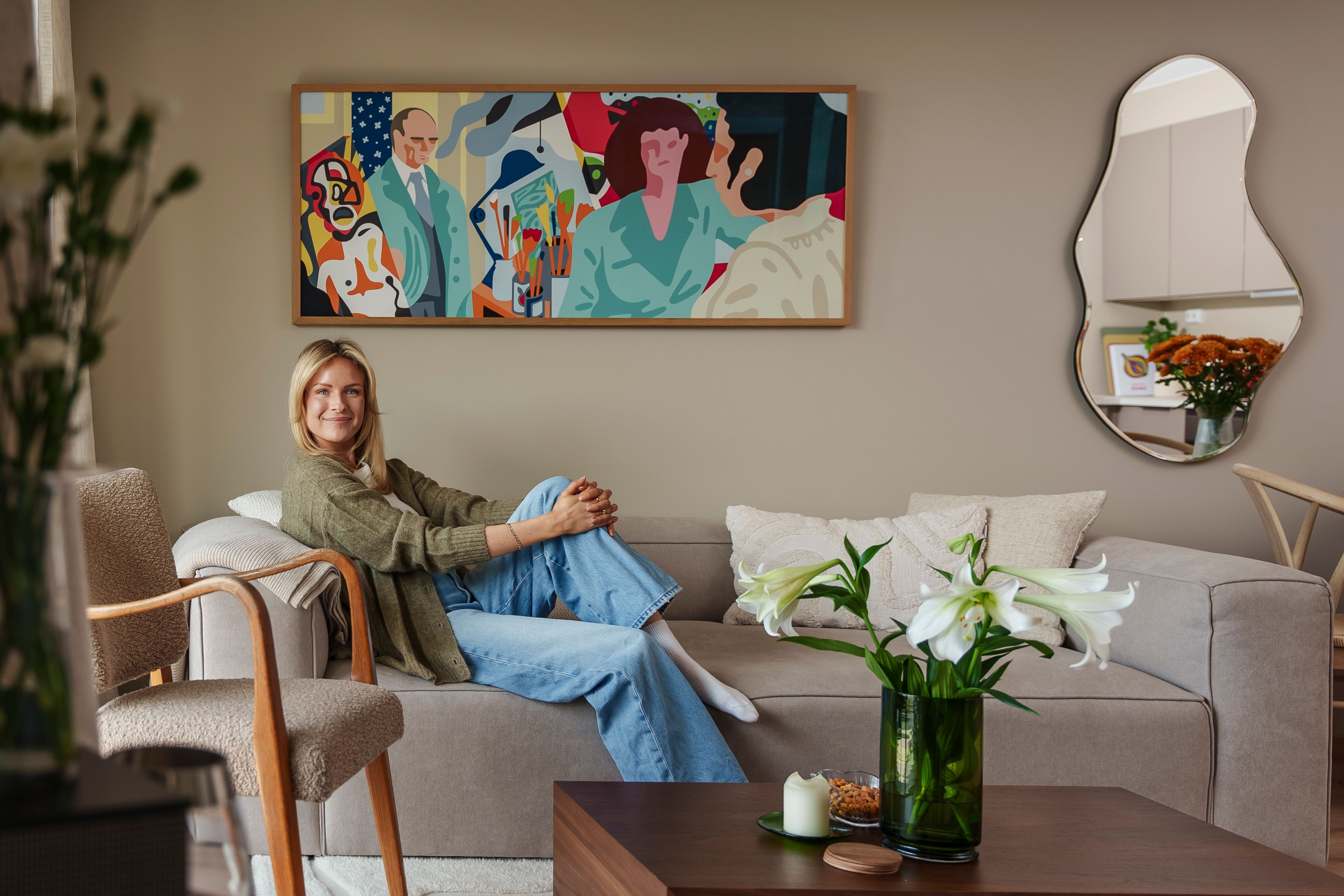 Brita sitter i sofaen sin i en lun og koselig stue.