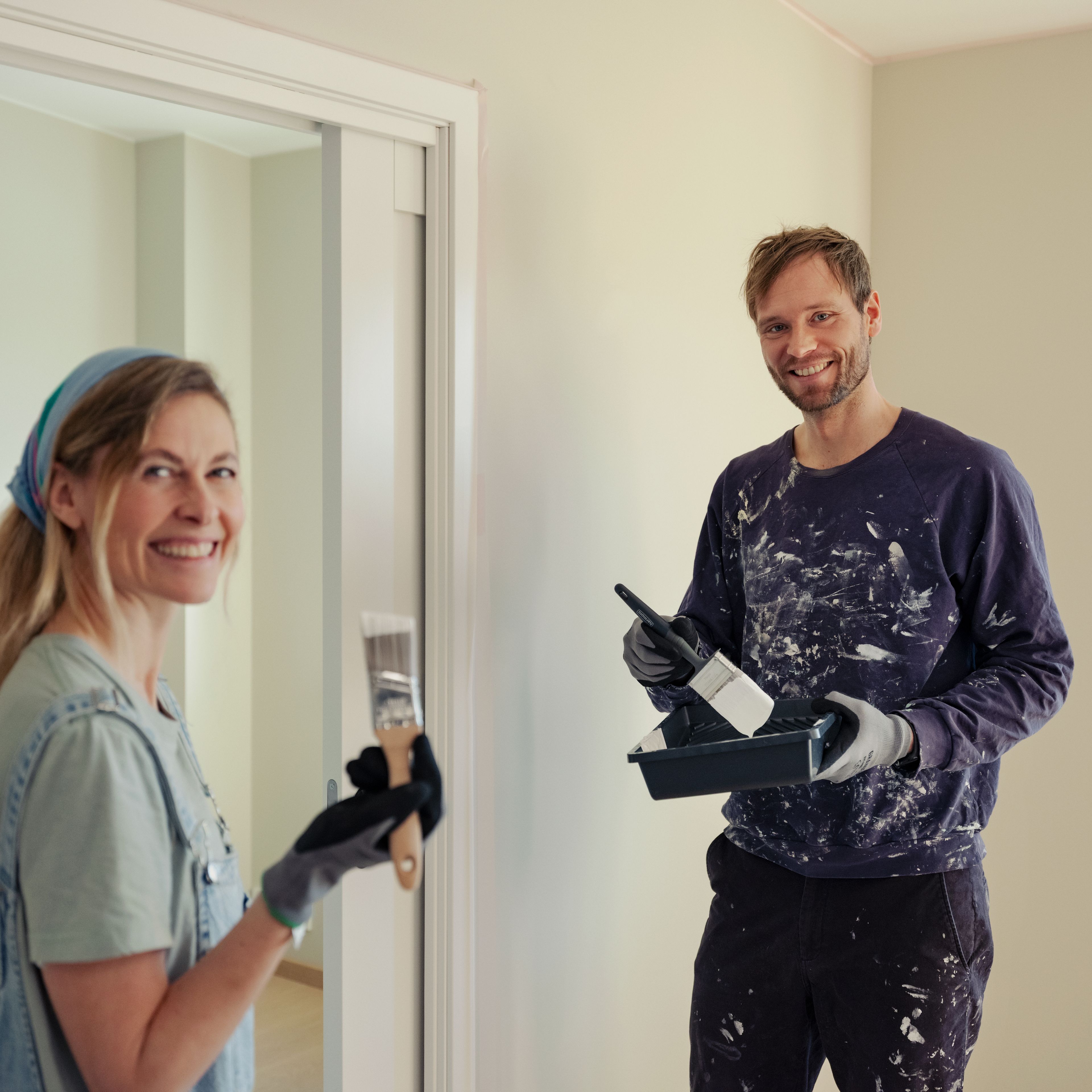 Et par maler stua. De ser på kameraet og smiler