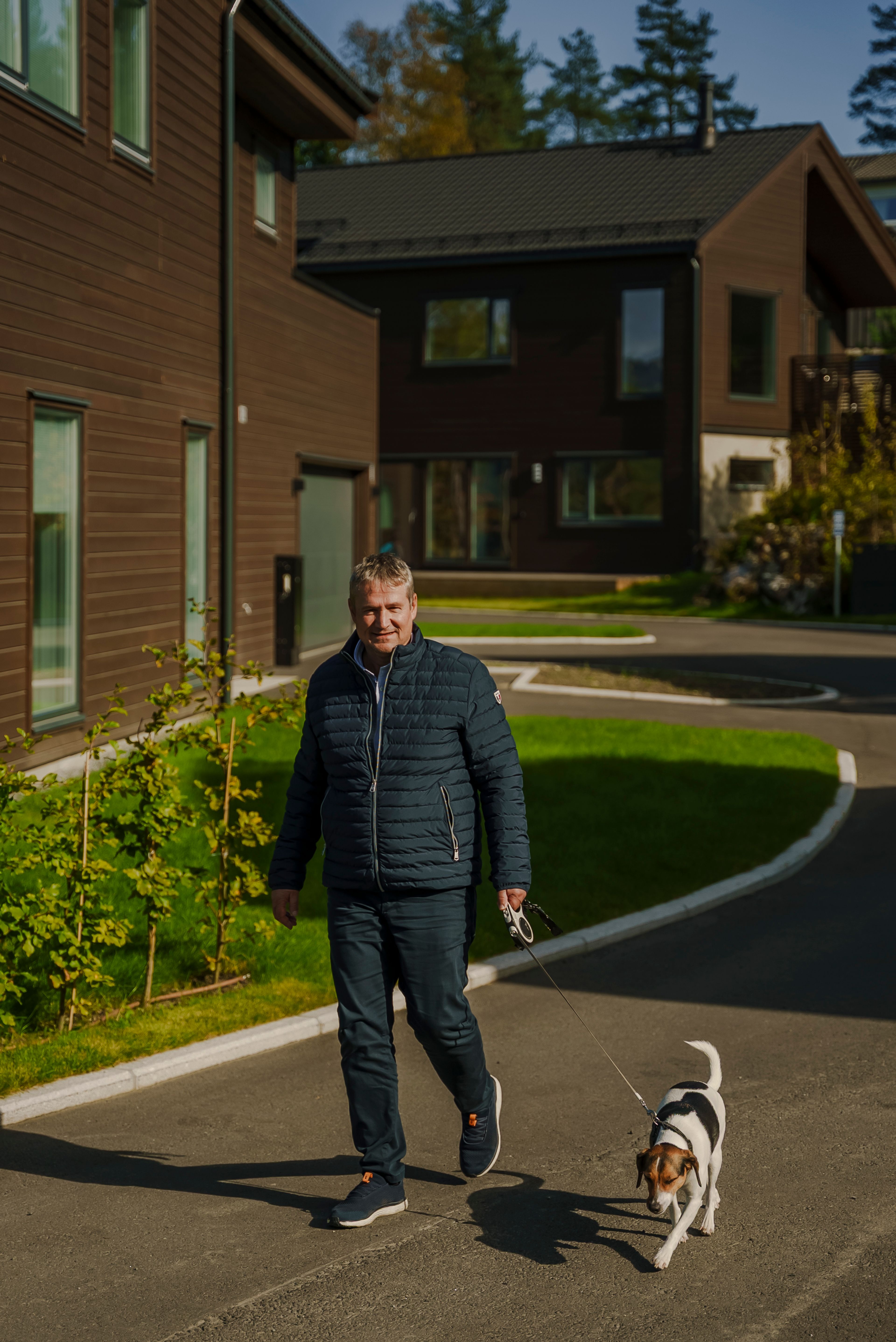 Tor Helge går tur med hunden foran det brune huset sitt