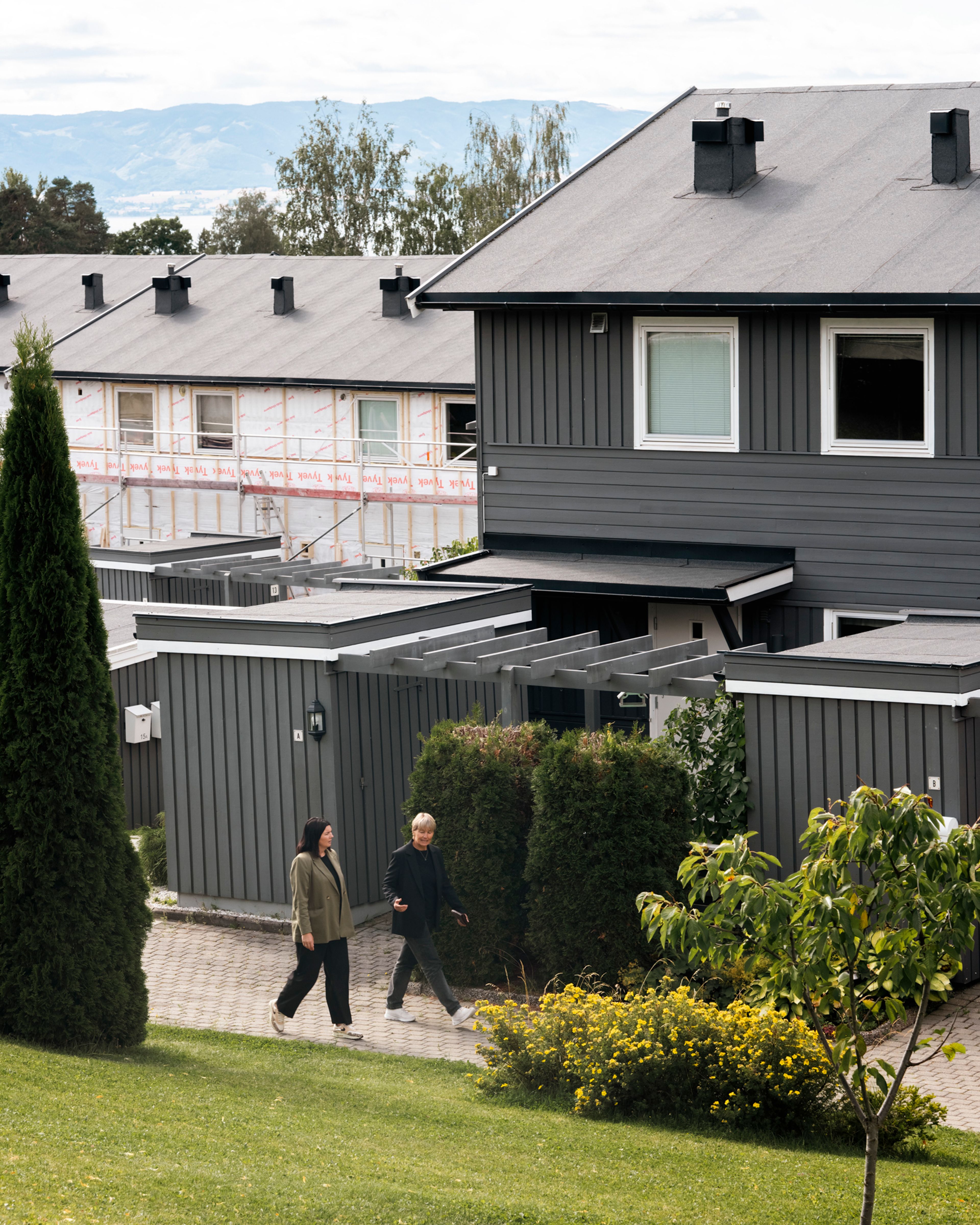 Rådgiverne fra OBOS går gjennom rekkehusanlegget i Delfinen borettslag, med både ferdige og pågående rehabiliteringsarbeider i bakgrunnen.