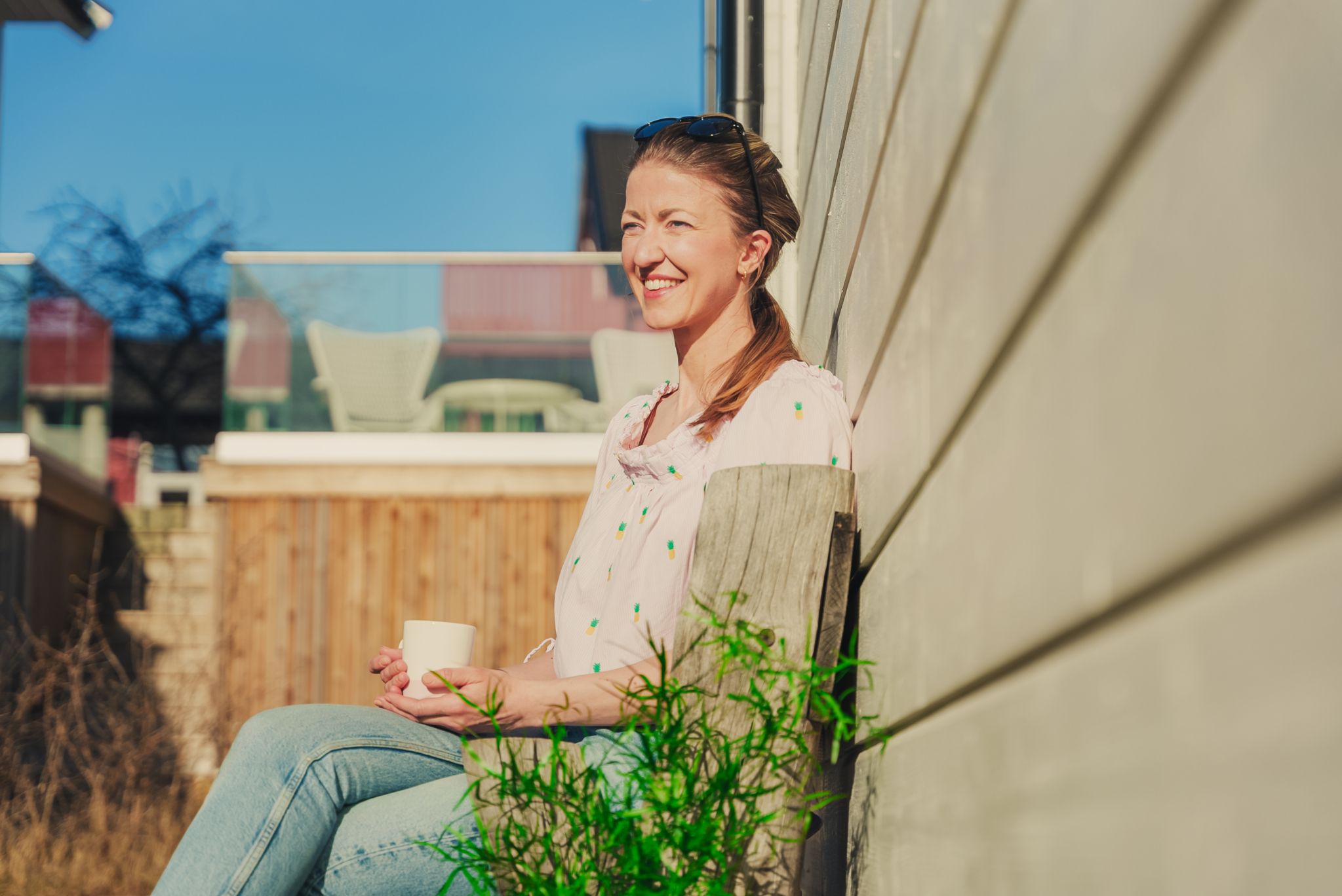 Siviløkonom Kjersti Grønseth sitter i solveggen med en kopp kaffe