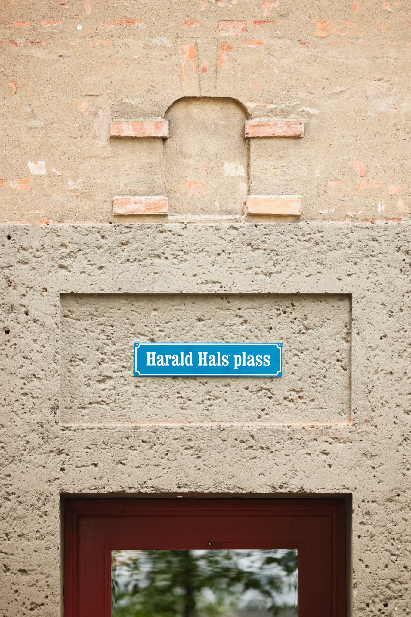 Et skilt med teksten "Harald Hals' plass" er satt opp på fasaden bak lommeparken.