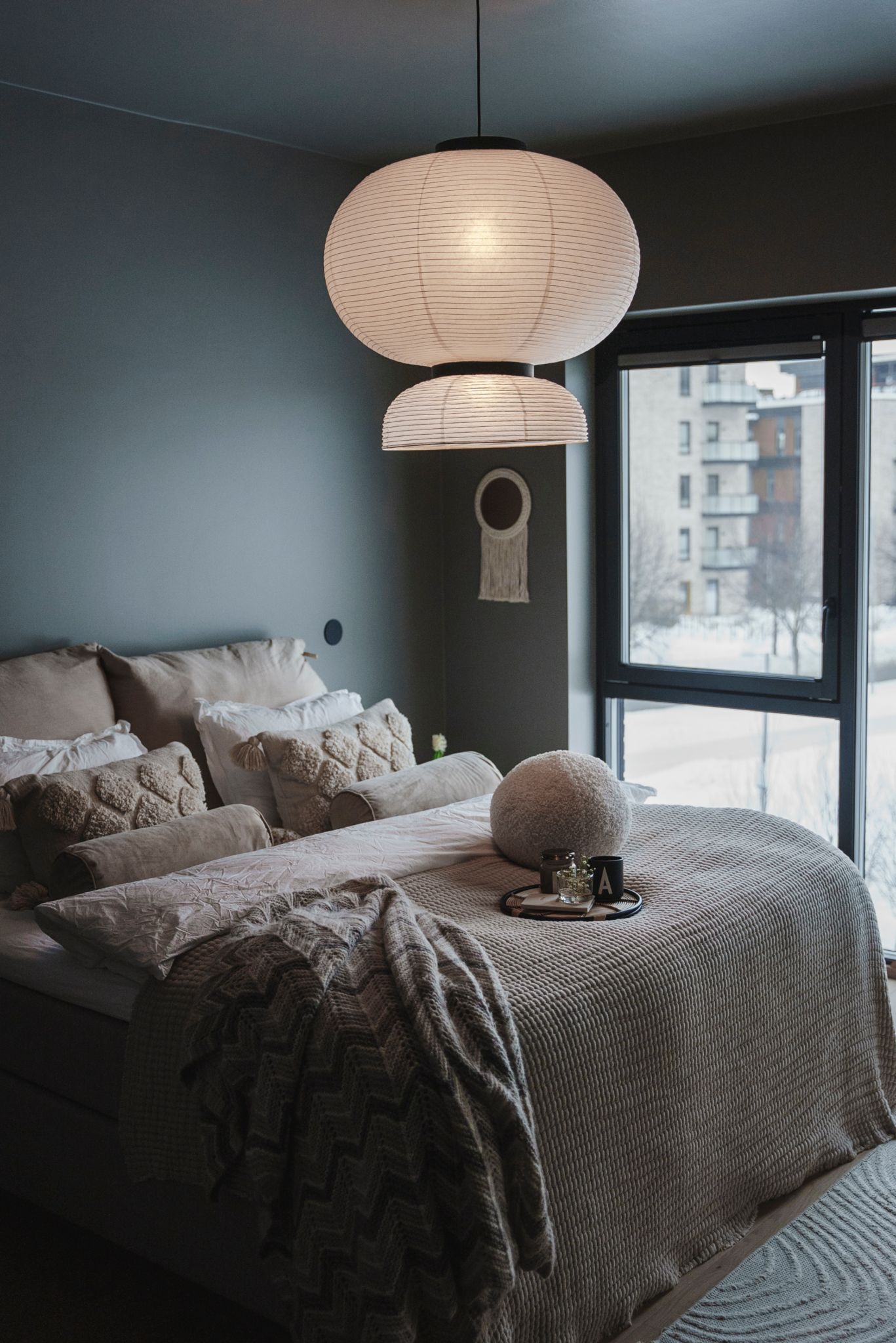 Bilde av et soverom med en beigekledd seng og taklampe av rispapir