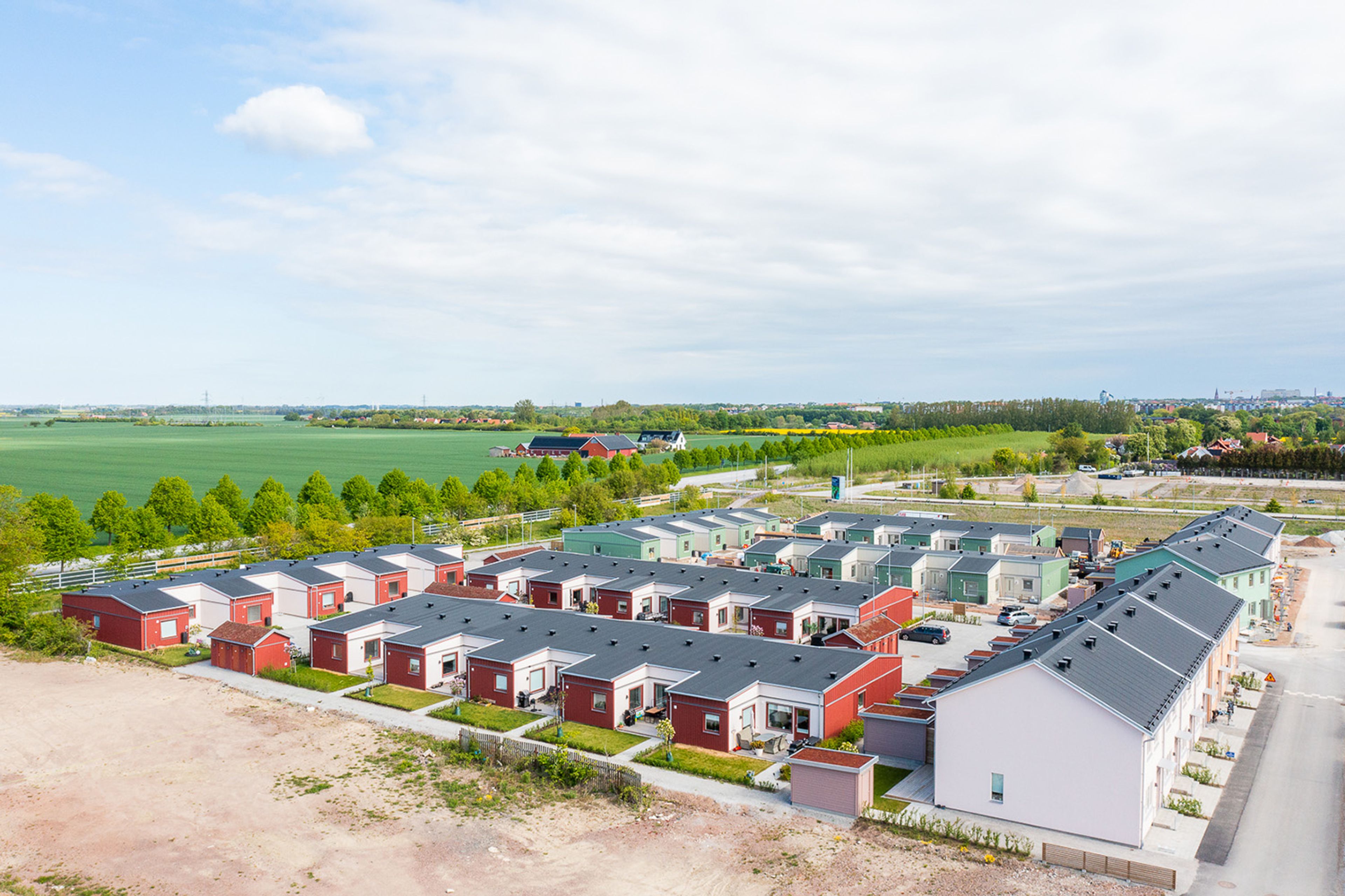 Flygfoto över bostadskvarter med radhus i rött, beige och grönt