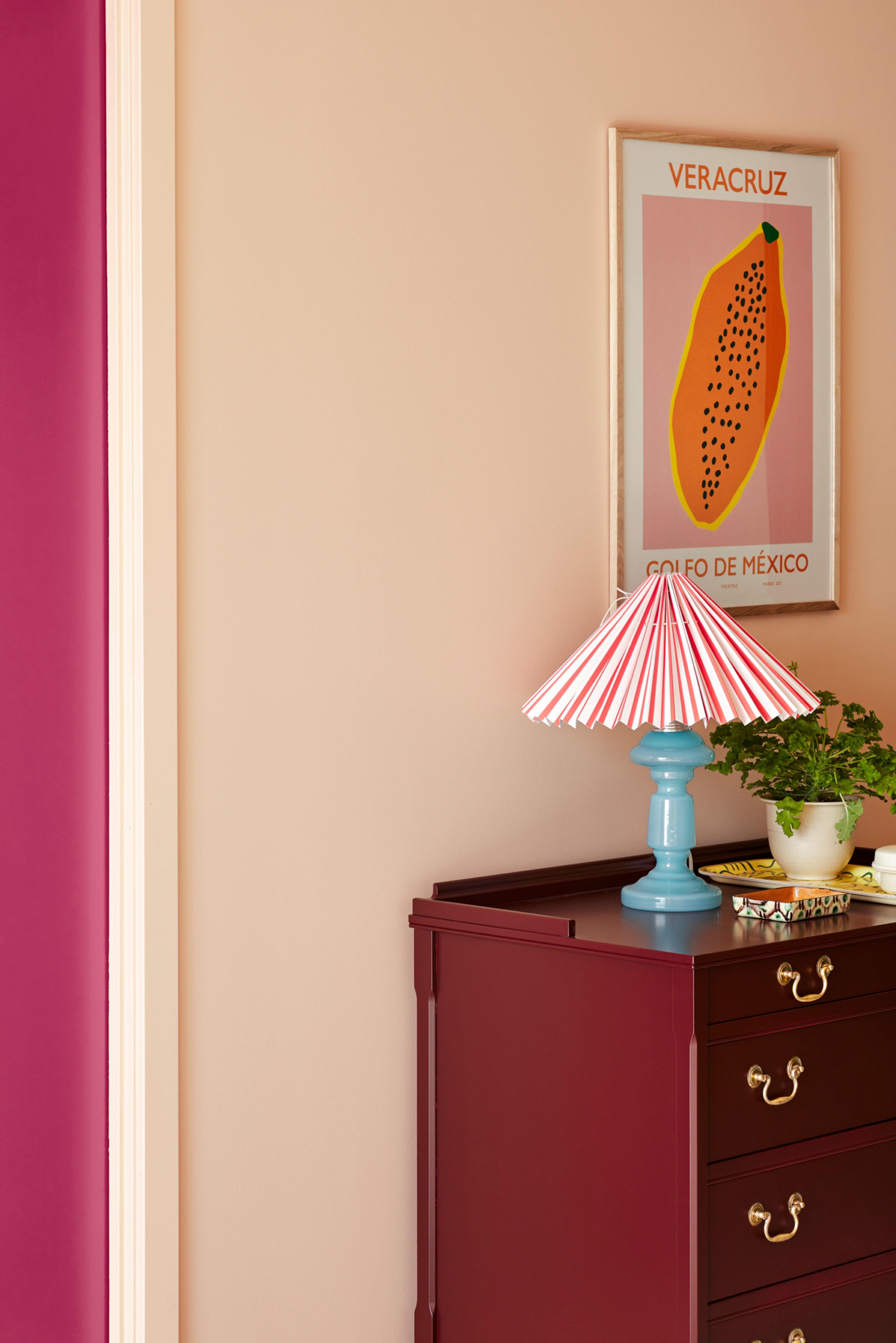 Detaljbilde av kommode med interiør som lampe, bilde og plante.