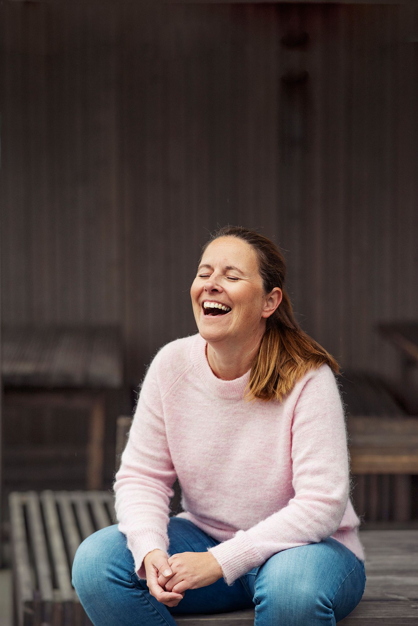Stina sitter på et bord og ler stort.