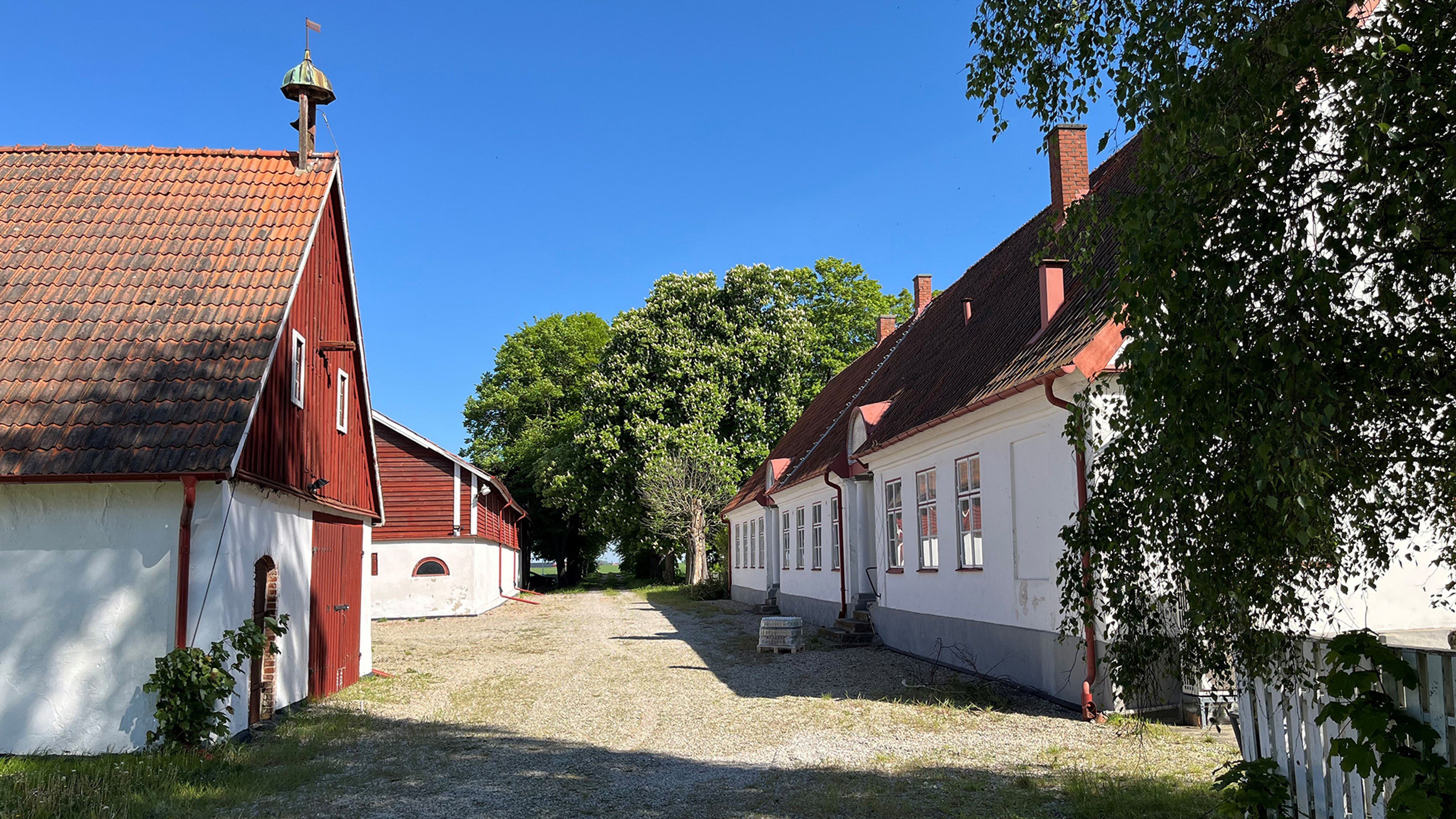 Foto på gårdsbyggnaderna med vit puts och röda tegeltak
