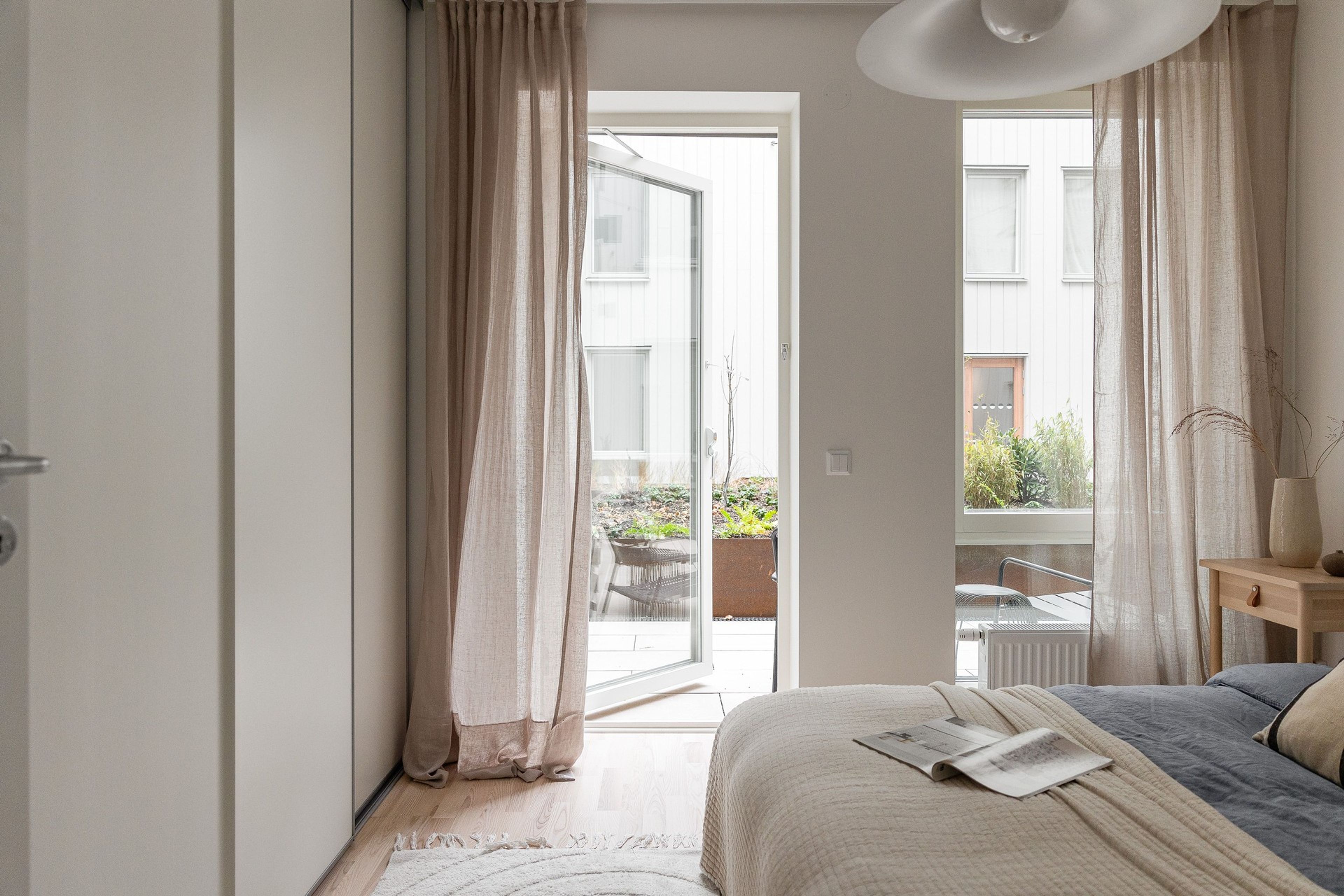 Sovrum med skjutdörrsgarderober och utgång till till innergård
