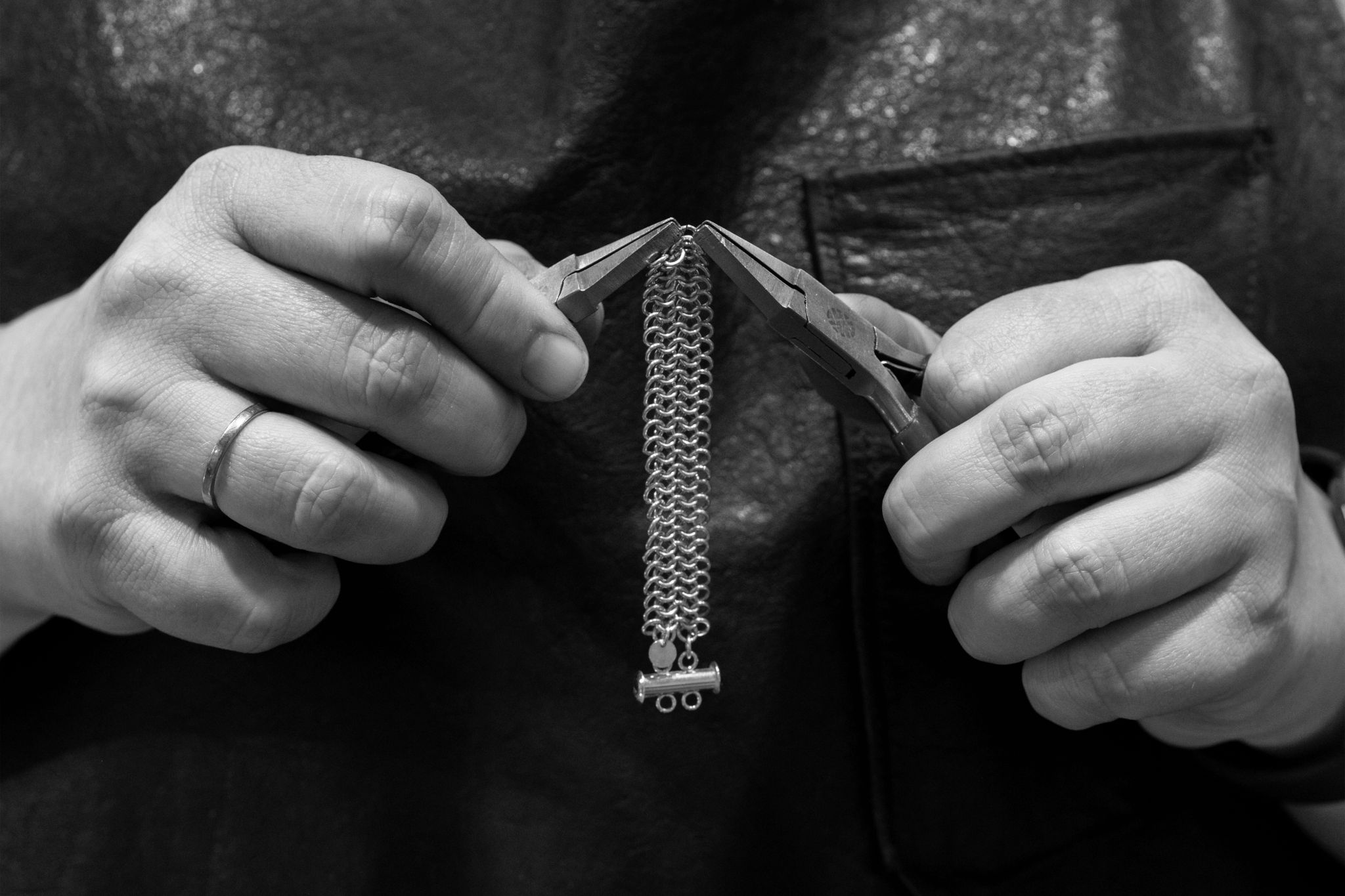 Svart/hvitt bilde av et smykke som blir bearbeidet med to tenger.