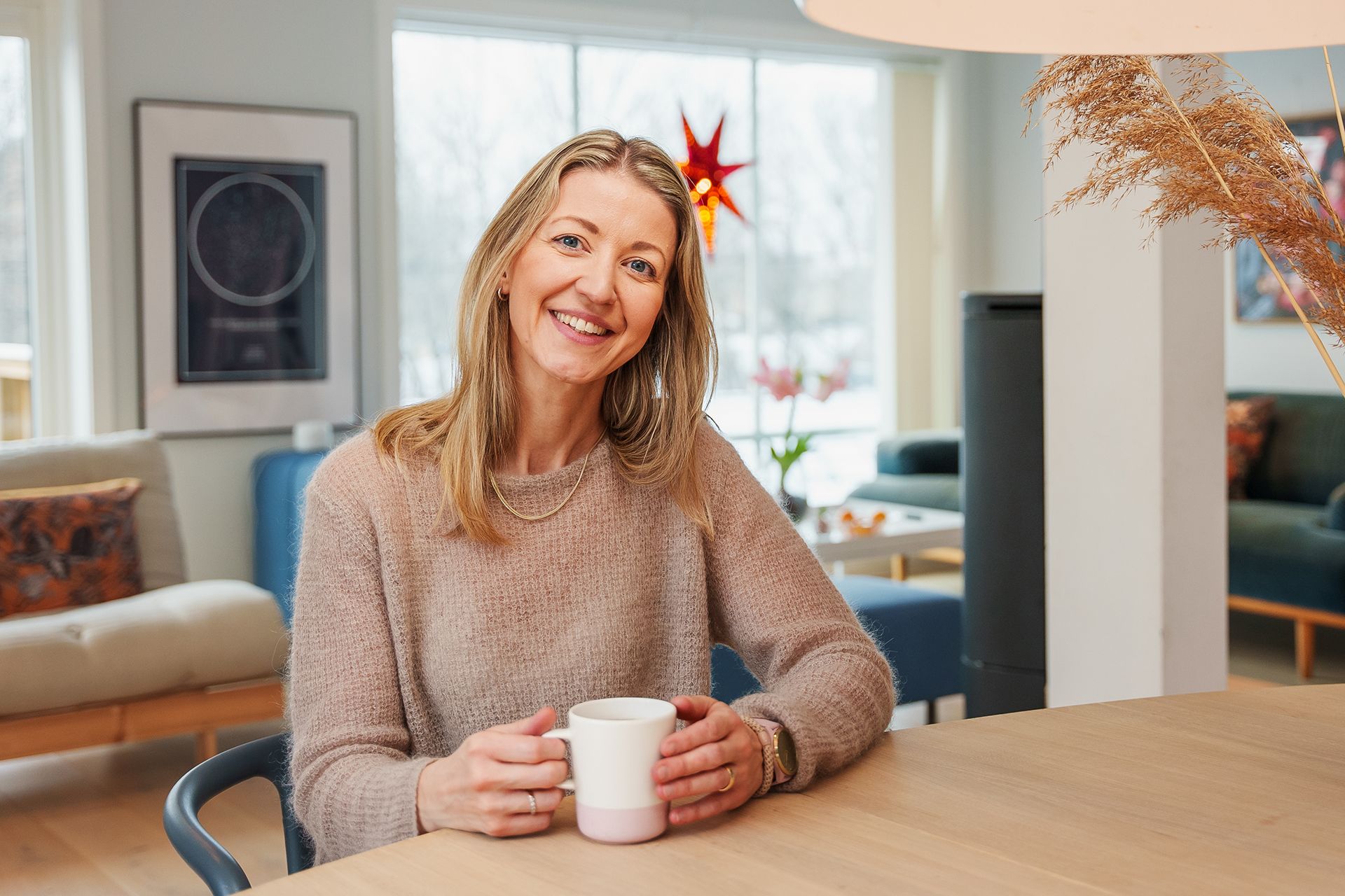 Forbrukerfrue, Kjersti Grønseth, sitter ved spisebordet hjemme. Foto.