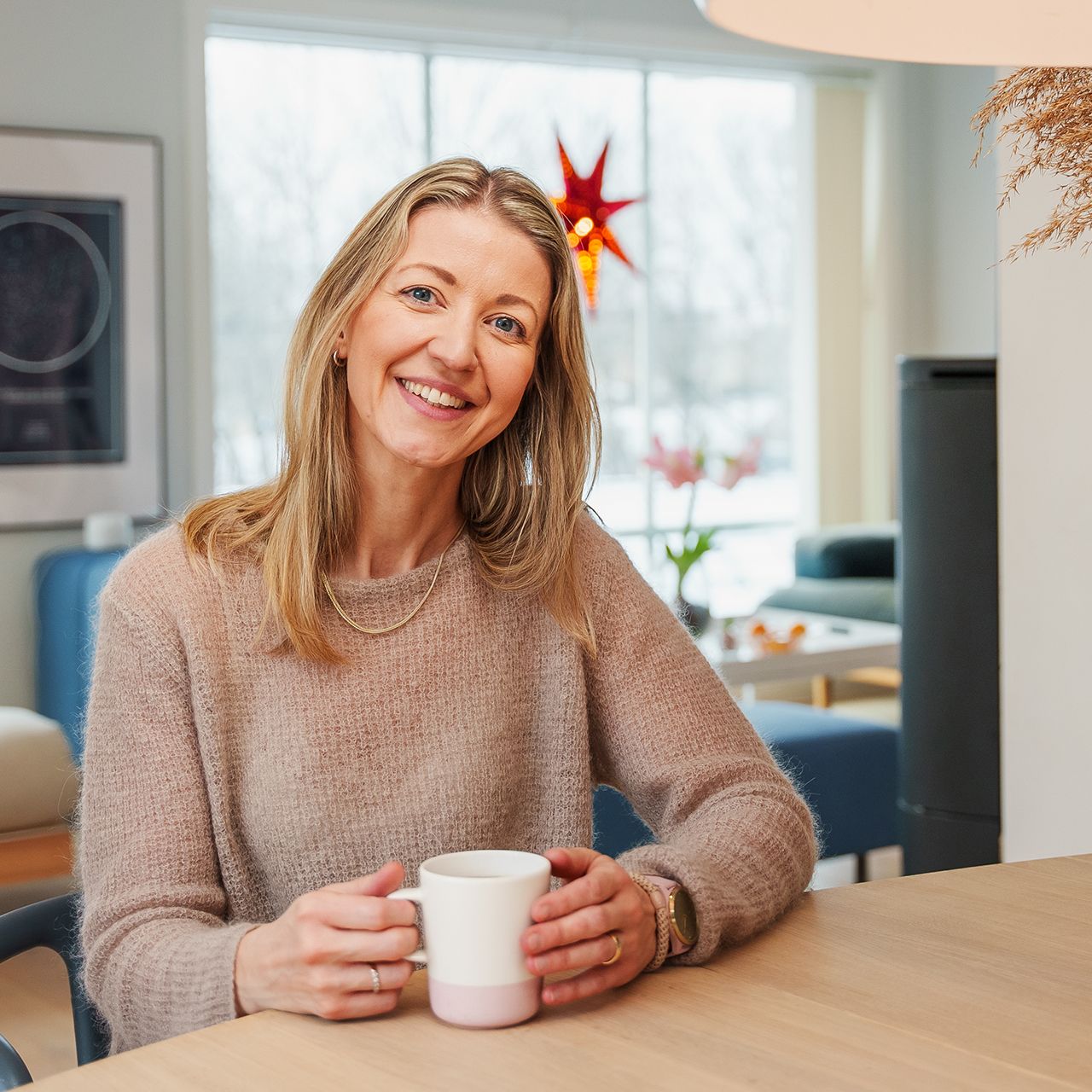Forbrukerfrue, Kjersti Grønseth, sitter ved spisebordet hjemme. Foto.