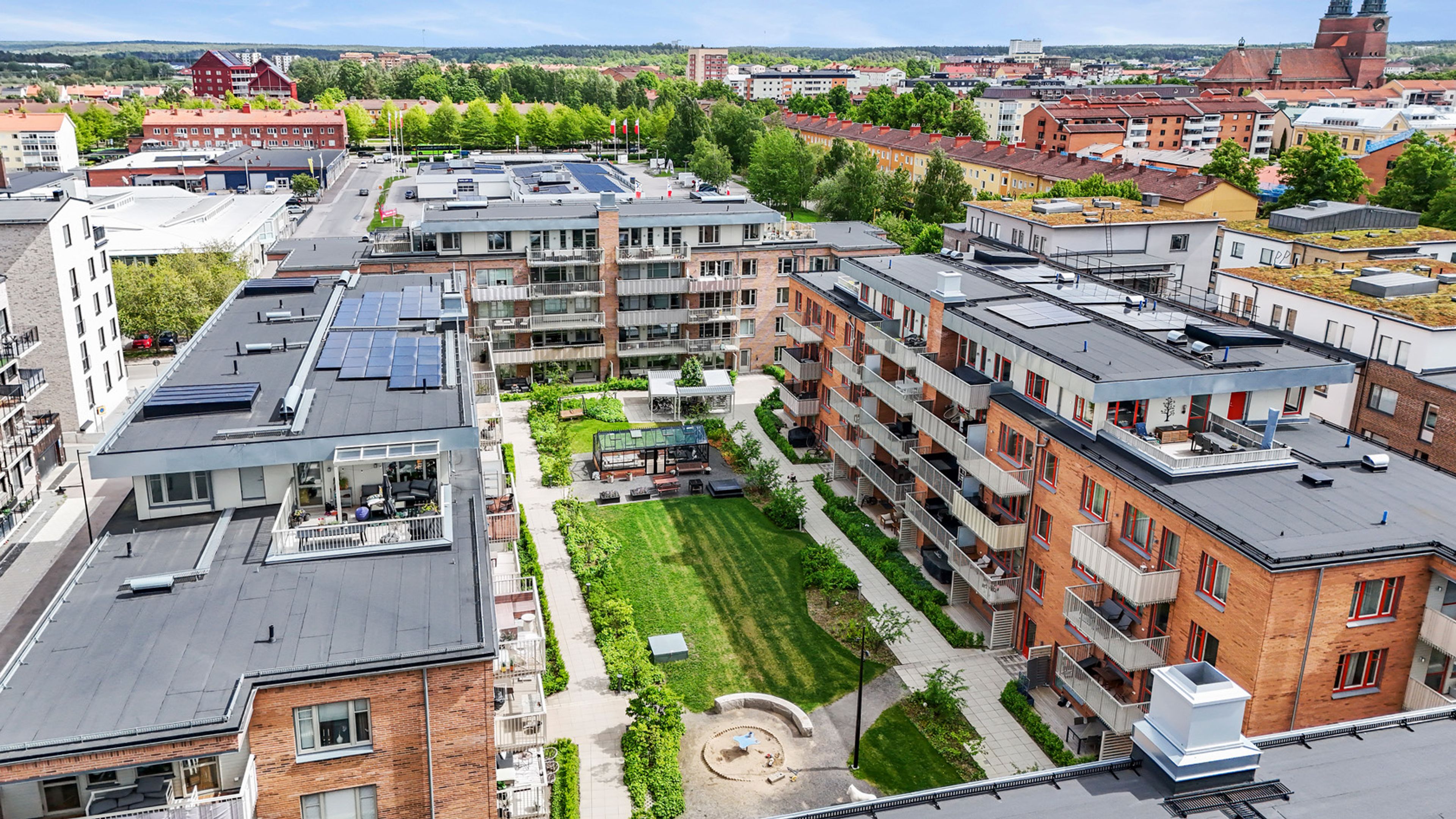 Flygfoto över kvarteret med lägenhetshus och en grönskande gemensam innegård