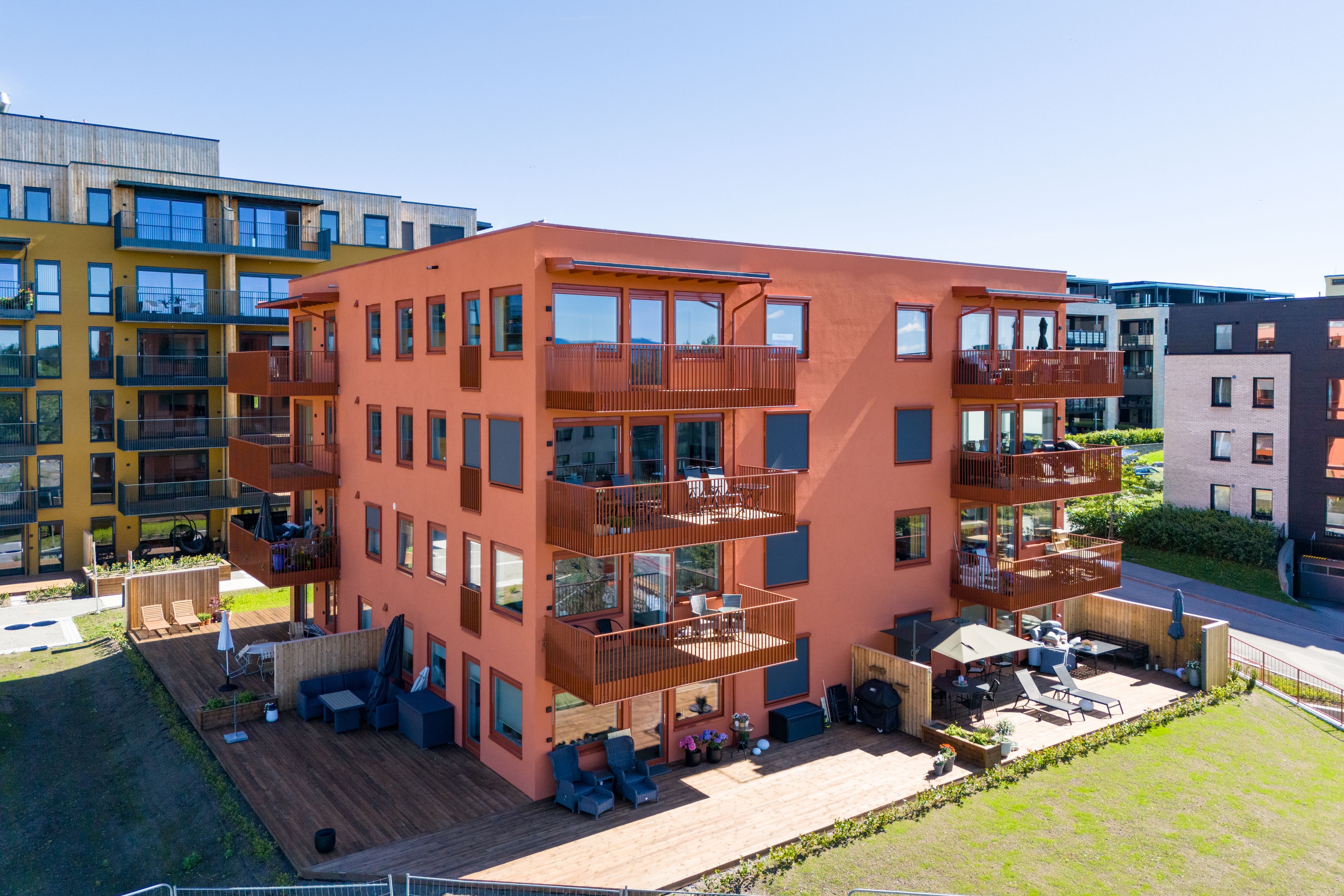 Fasaden til hus C i Stålverket Torg i terracotta-farge og balkonger i sola.