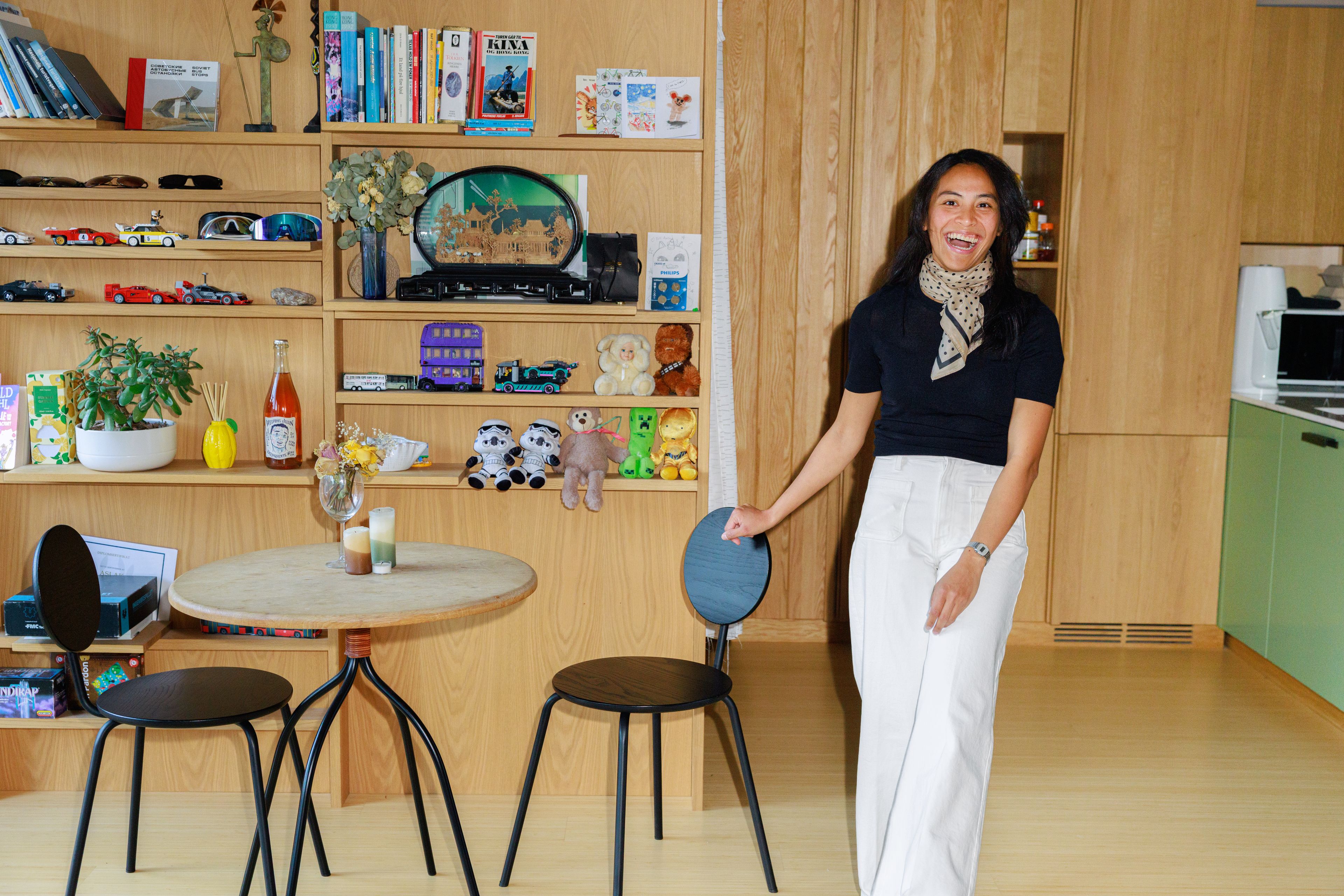 Areej Ludo som står foran en hylle full av fargerike leker og figurer. 