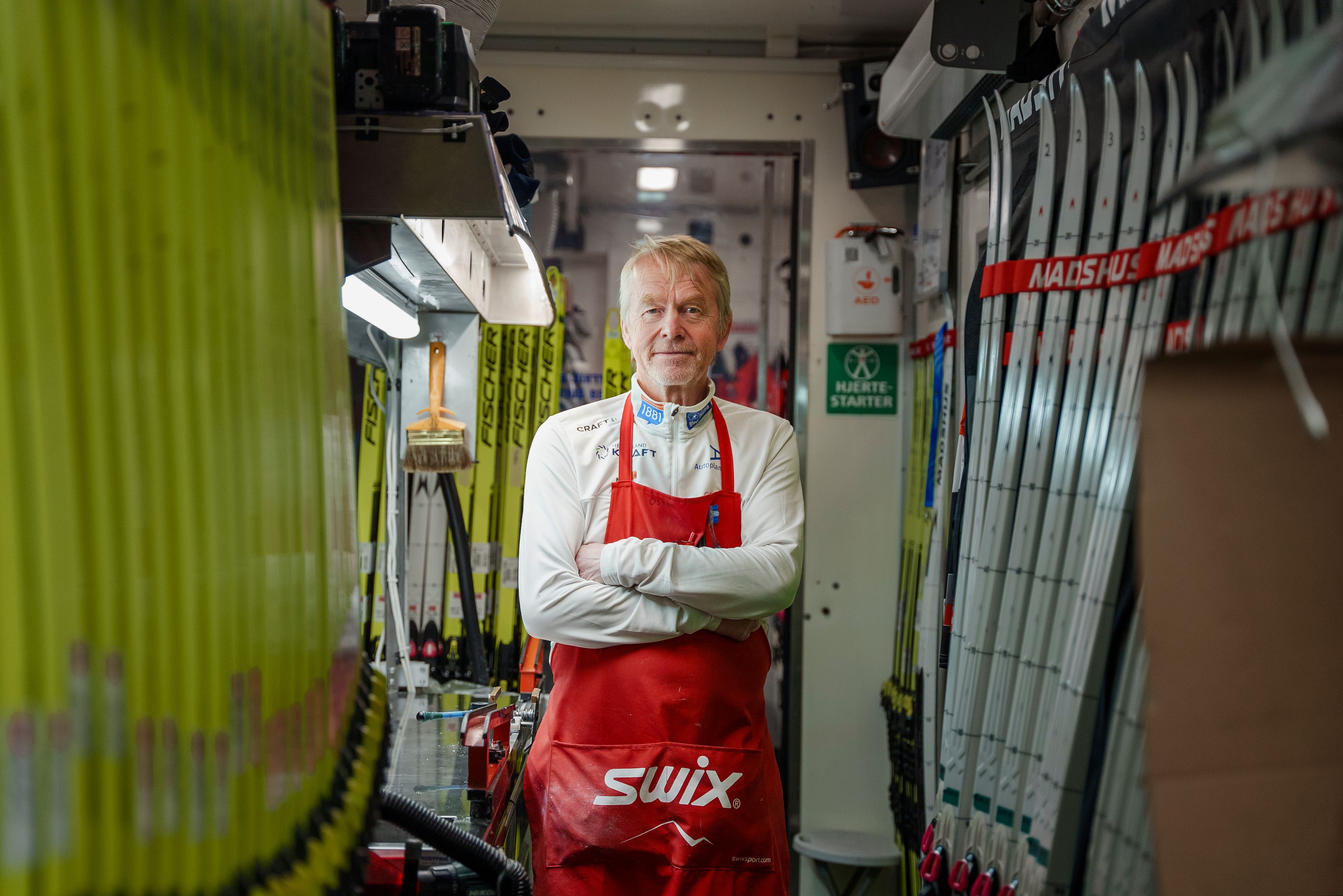 Oskar Håland står midt i smøretraileren med armene i kryss og ski linet langs veggene