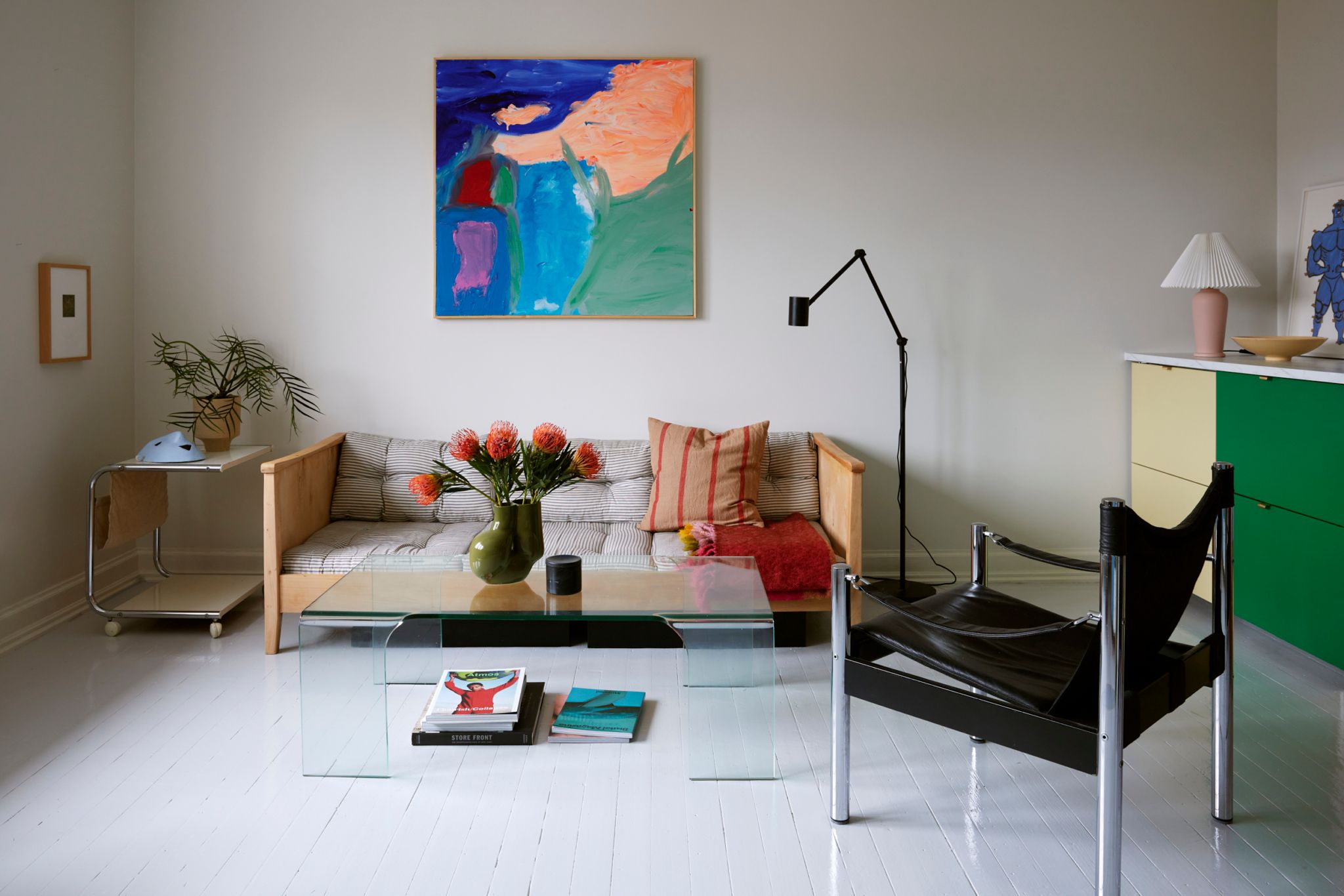 Bildet viser en stue med hvitmalt gulv og møbler i ulike farger og fasonger.