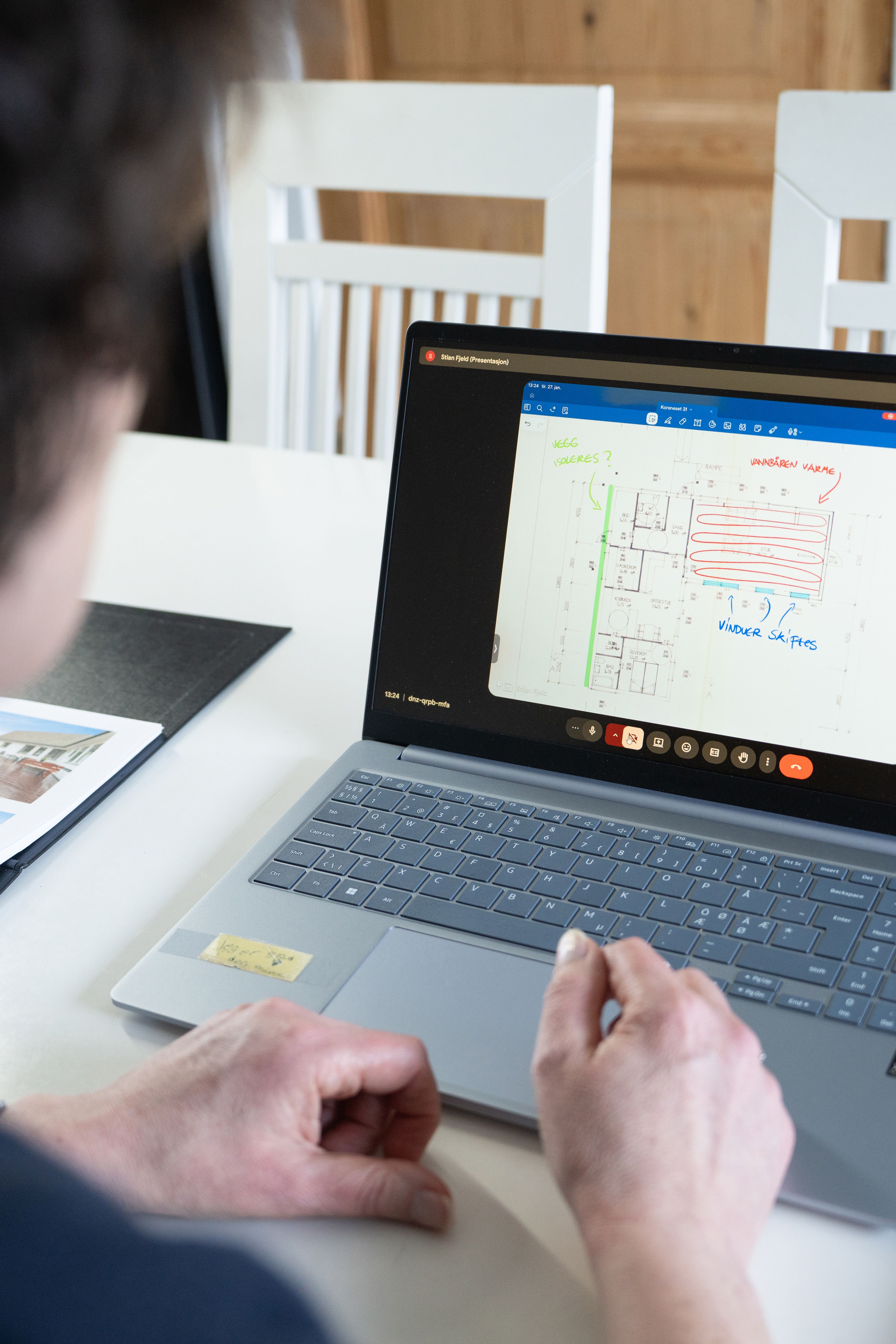 Kvinne sitter og ser på en PC med bilde av plantegningen til boligen.