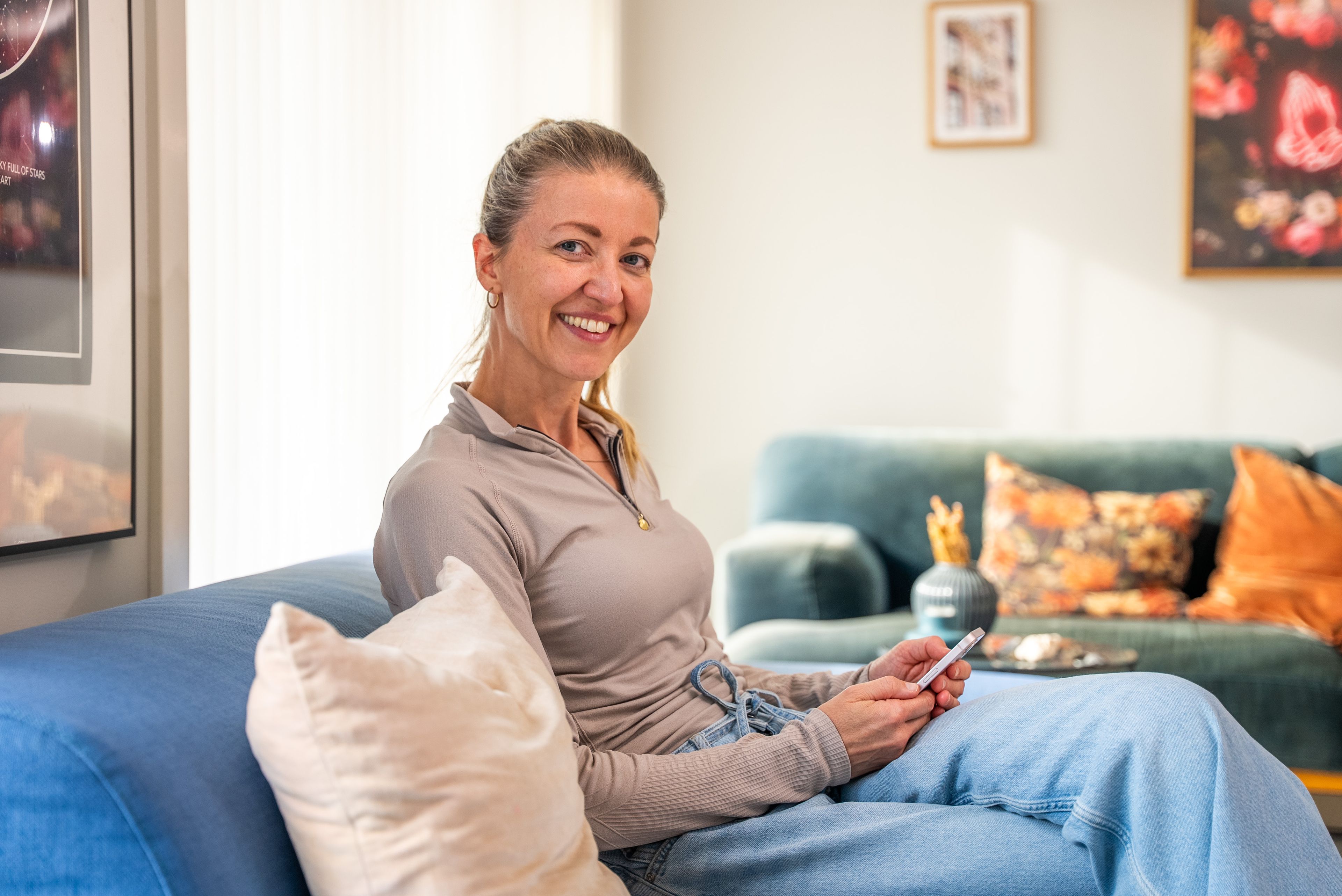 Forbrukerøkonom Kjersti Grønseth i sofaen med mobilen i hånda