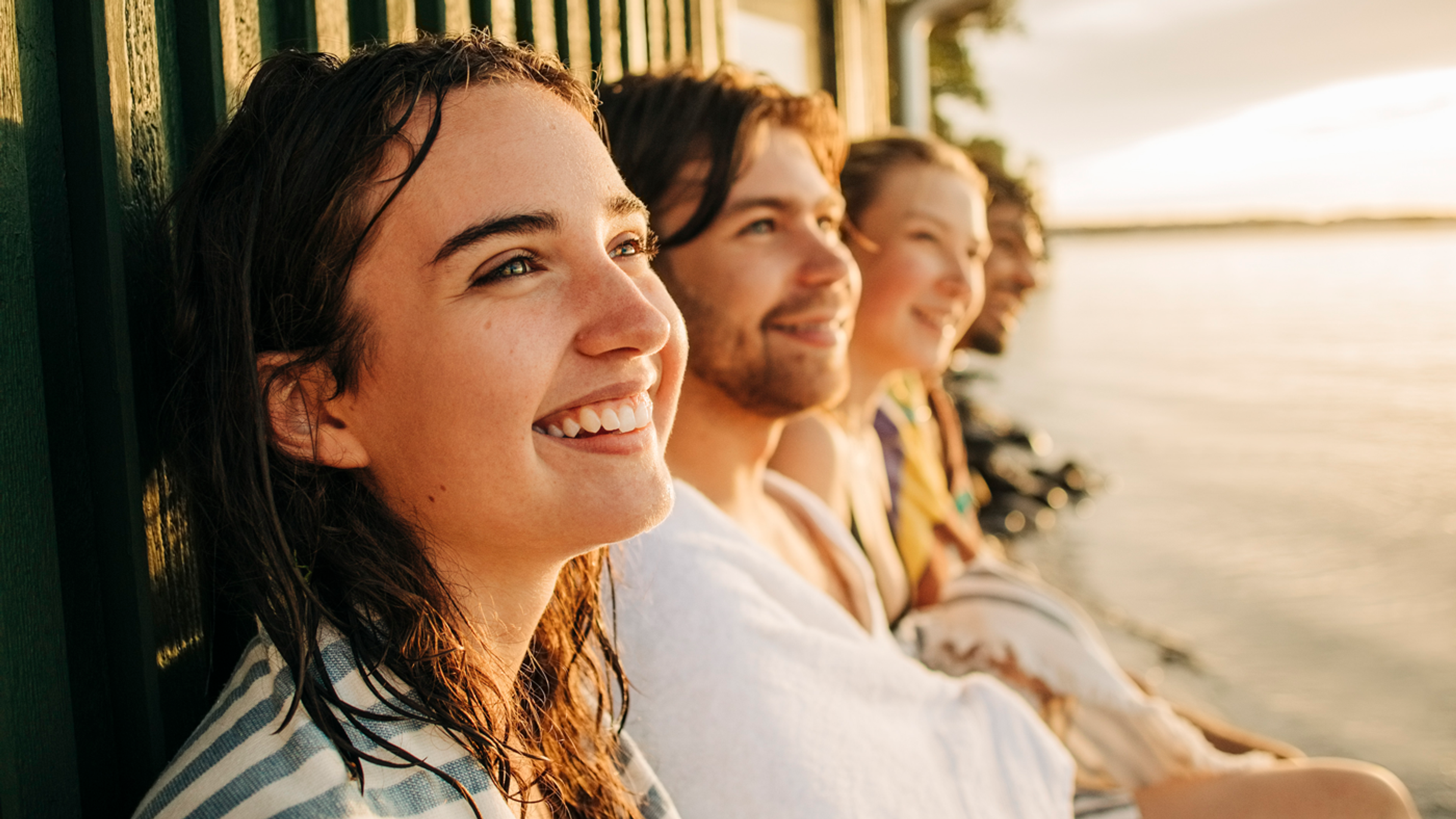 4 personer som just badat och sitter precis vid strandkanten