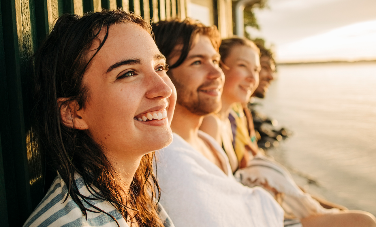 4 personer som just badat och sitter precis vid strandkanten