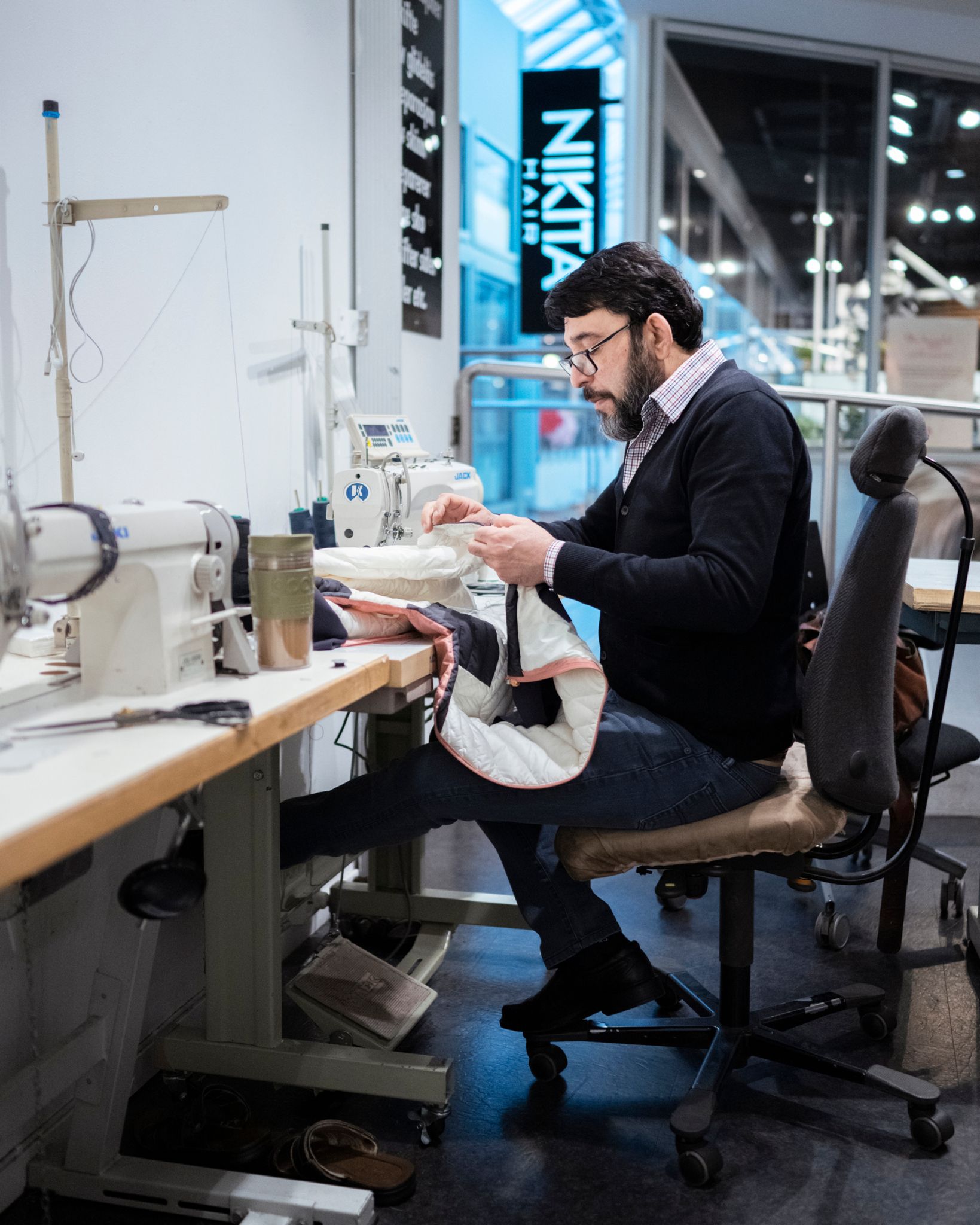 Bildet viser Same Safdari som sitter og syr ved maskinen.