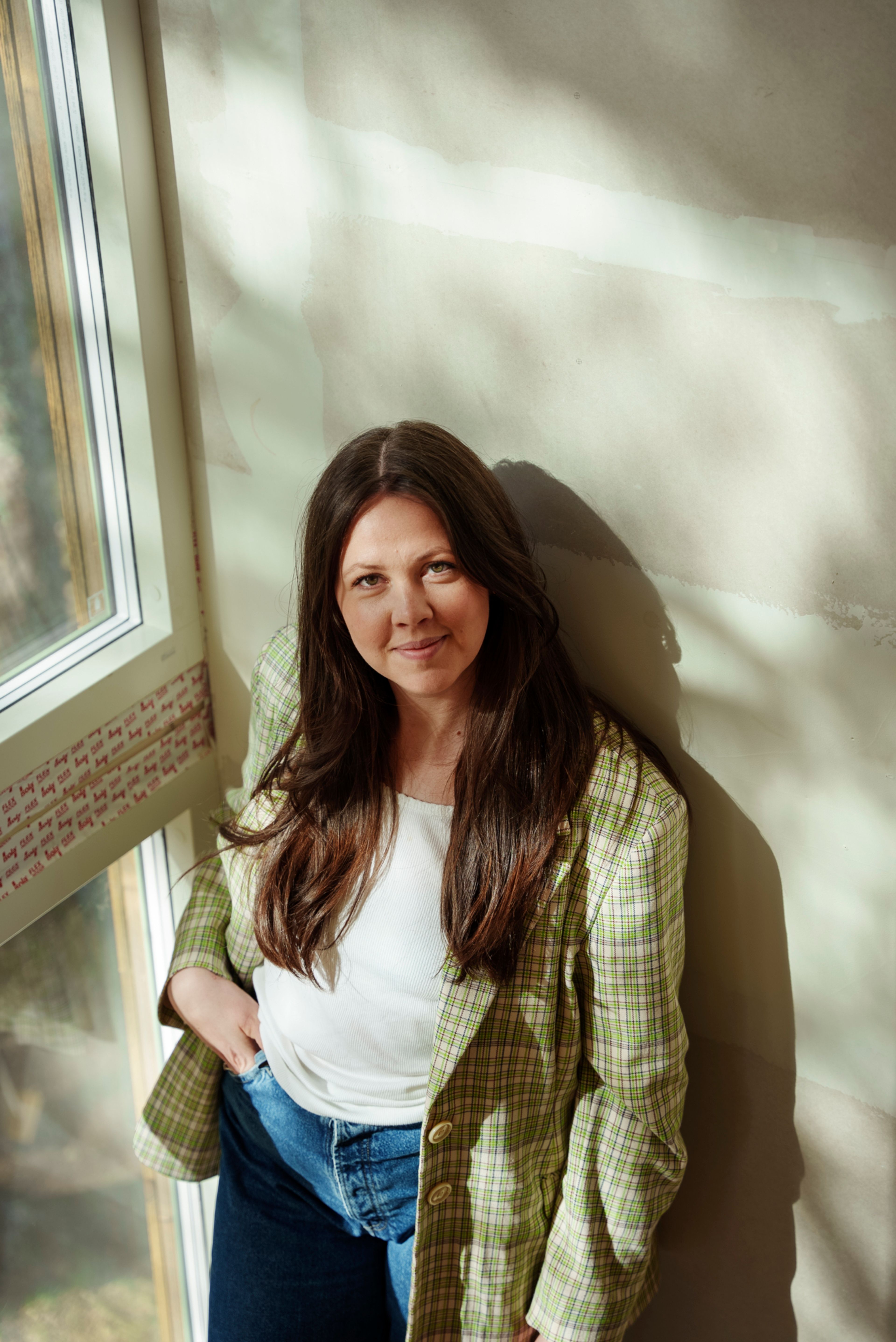 Bilde av en kvinne med langt brunt hår som står i trappa i huset sitt.